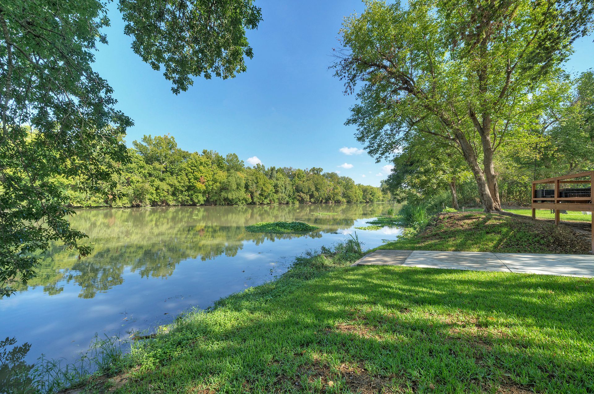 A lake surrounded by trees and grass on a sunny day