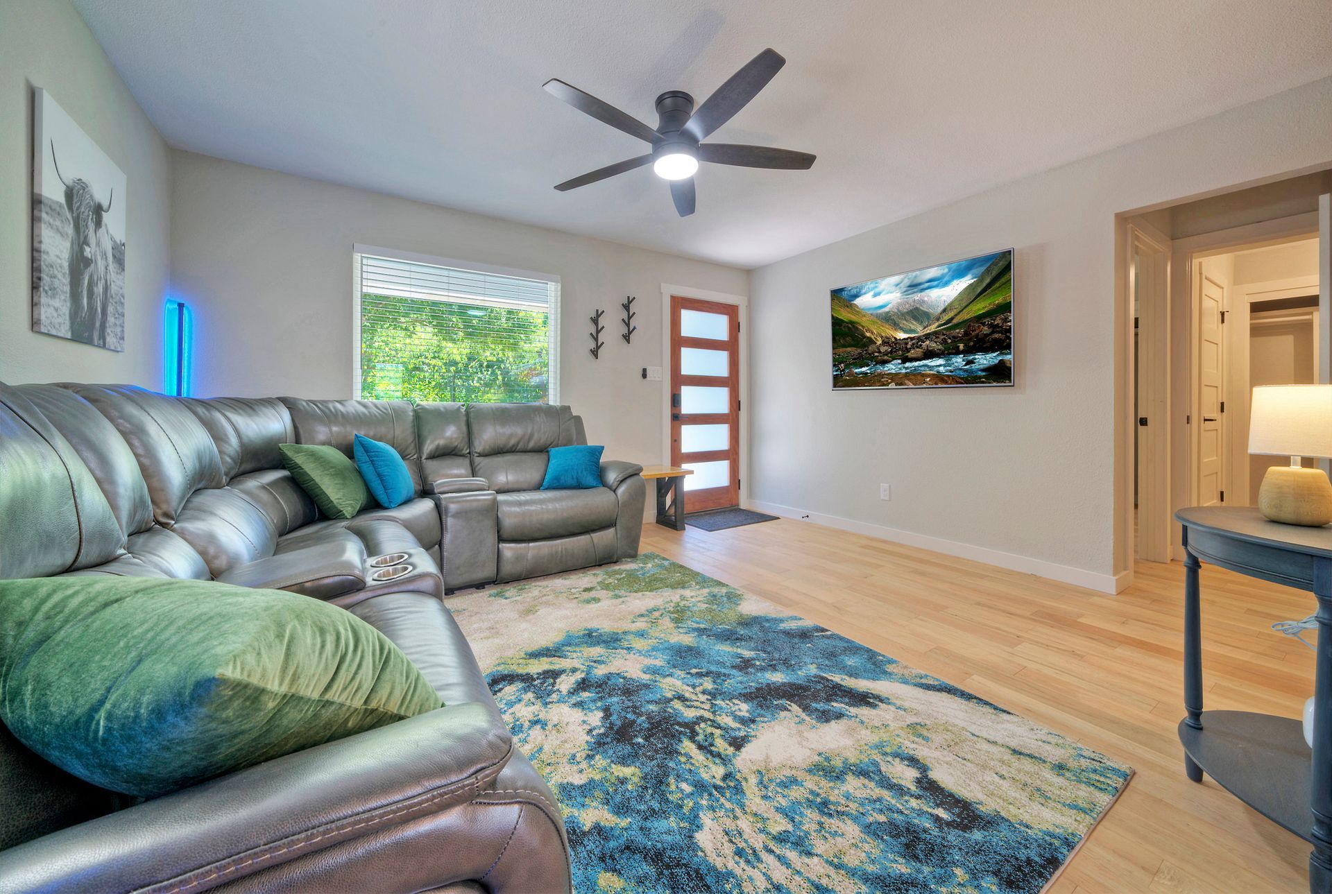 A living room with a couch , rug , television and ceiling fan.