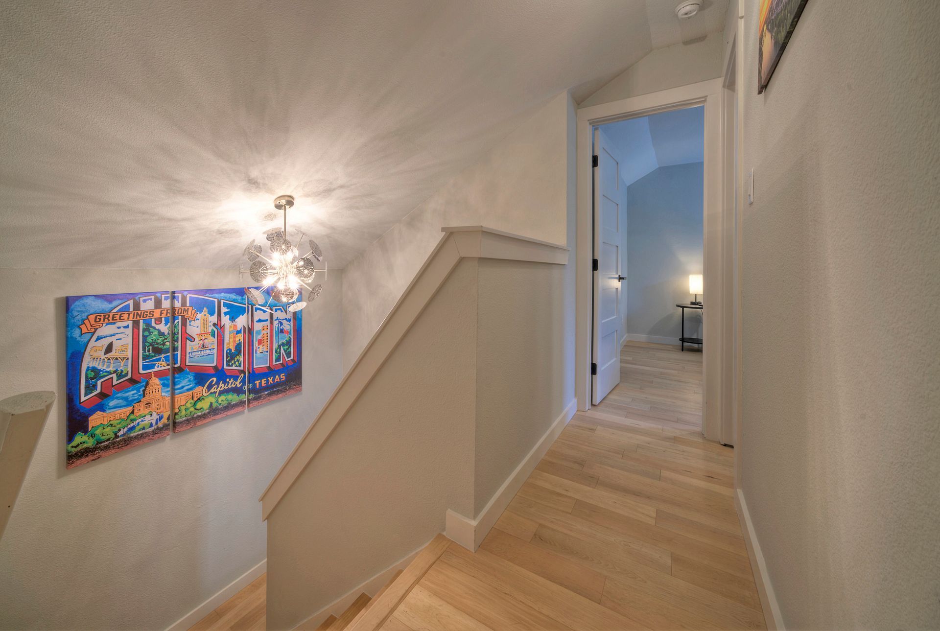 A hallway with stairs and a painting on the wall.