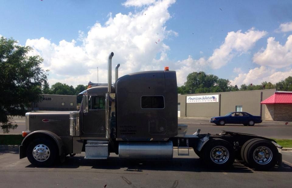 A semi truck is parked in a parking lot in front of a building.