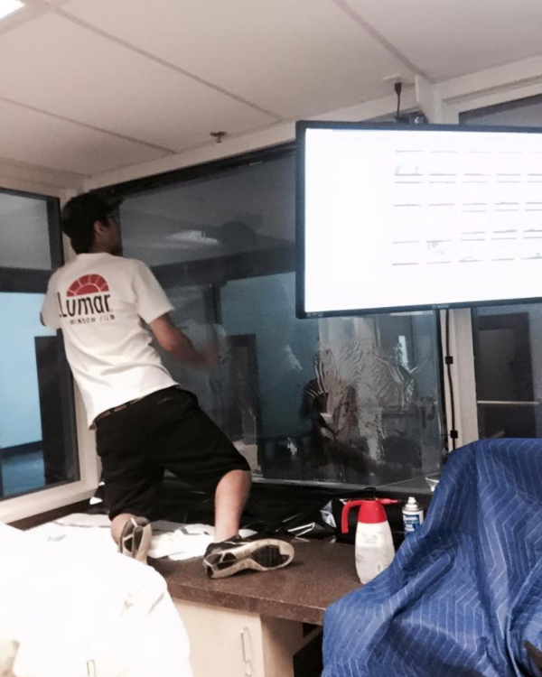A man in a lumox shirt is cleaning a window