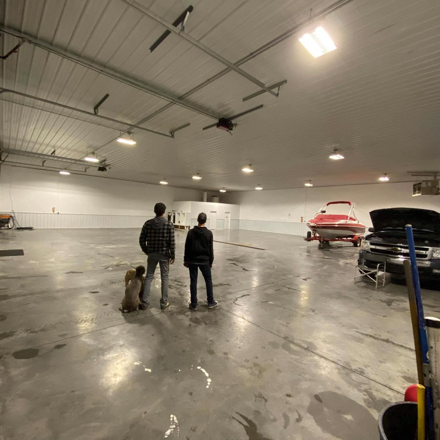 Three people standing in a garage with a boat in the background