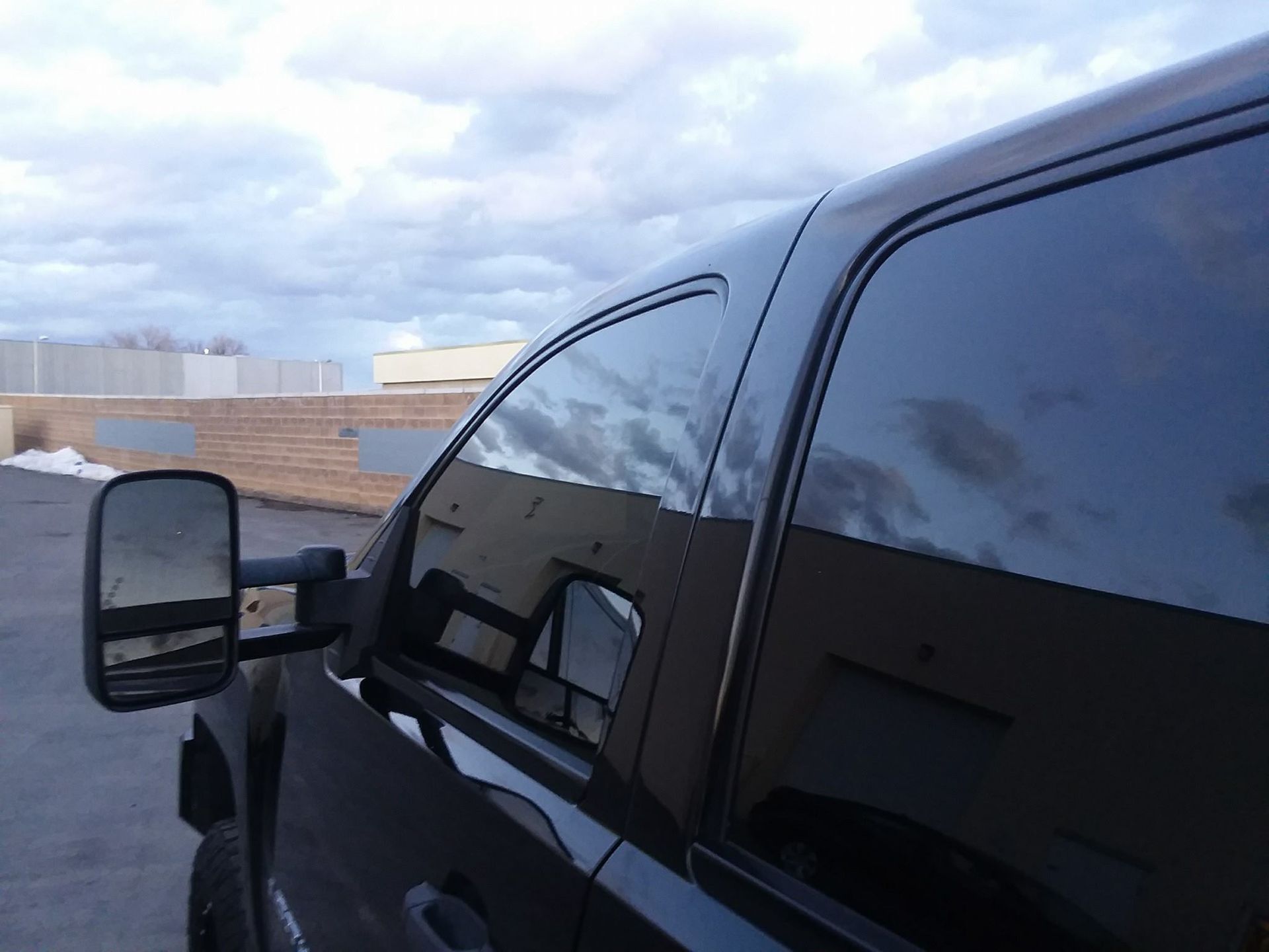 A black truck with a tow mirror is parked in a parking lot