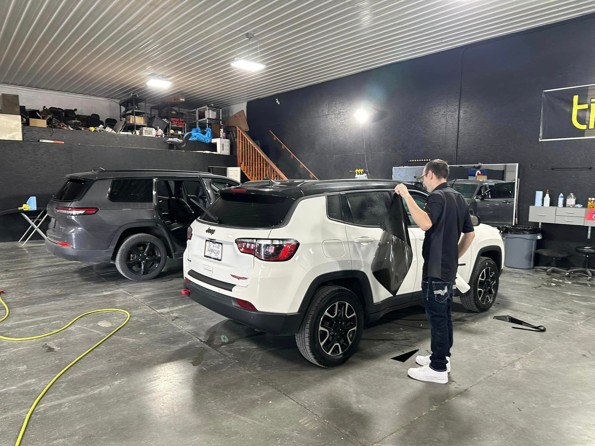 A man is standing next to a white jeep in a garage.