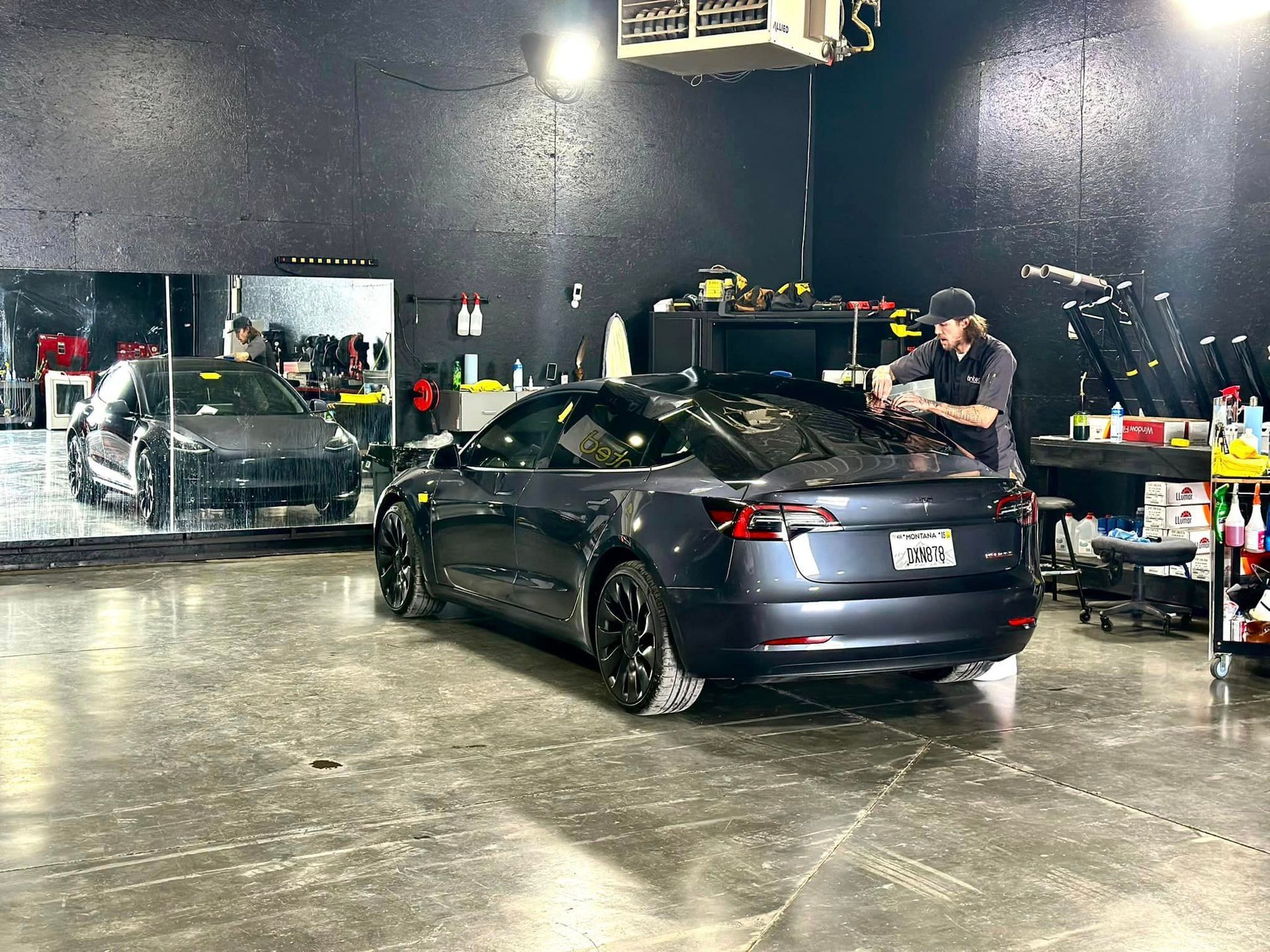 A man is working on a tesla model 3 in a garage.