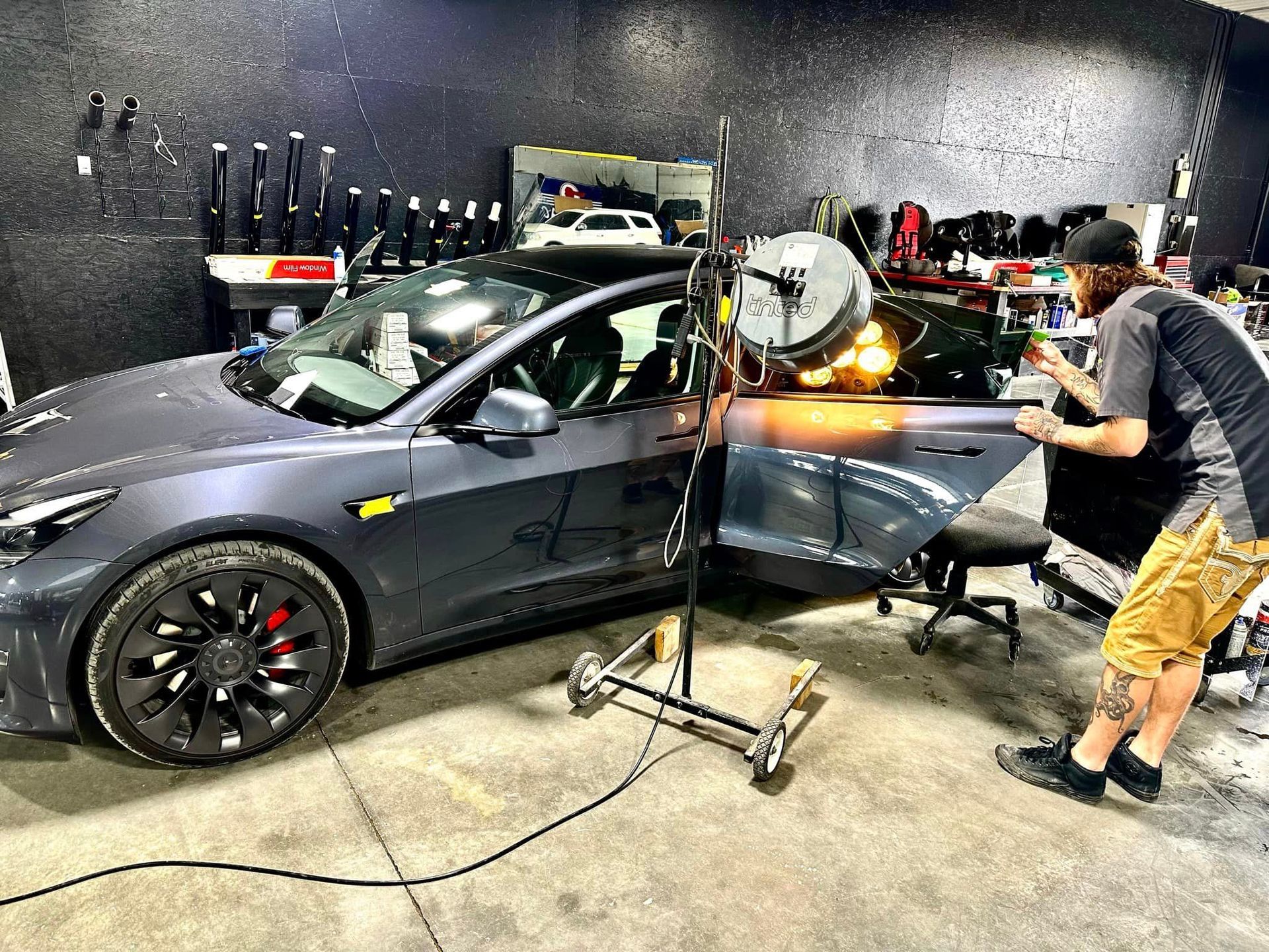 A man is working on a tesla model y in a garage.