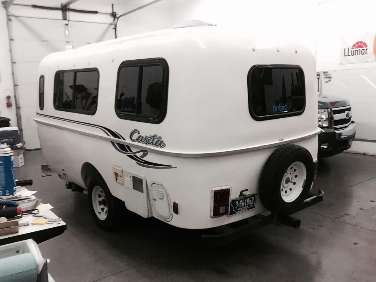 A small white camper is parked in a garage