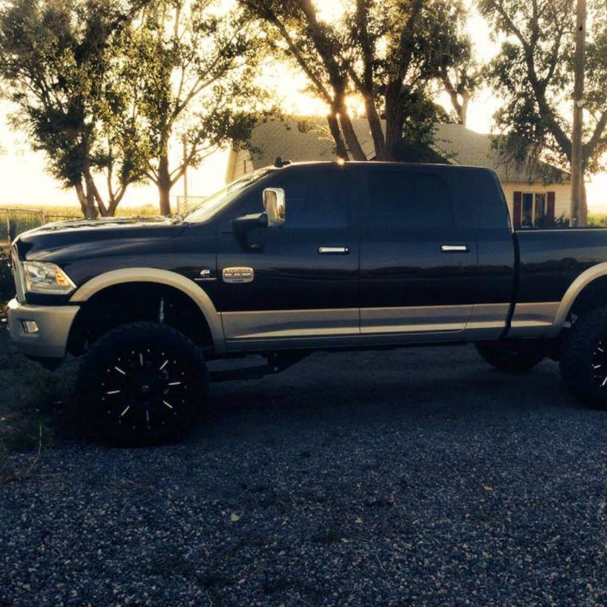 A black truck is parked on gravel in front of a house