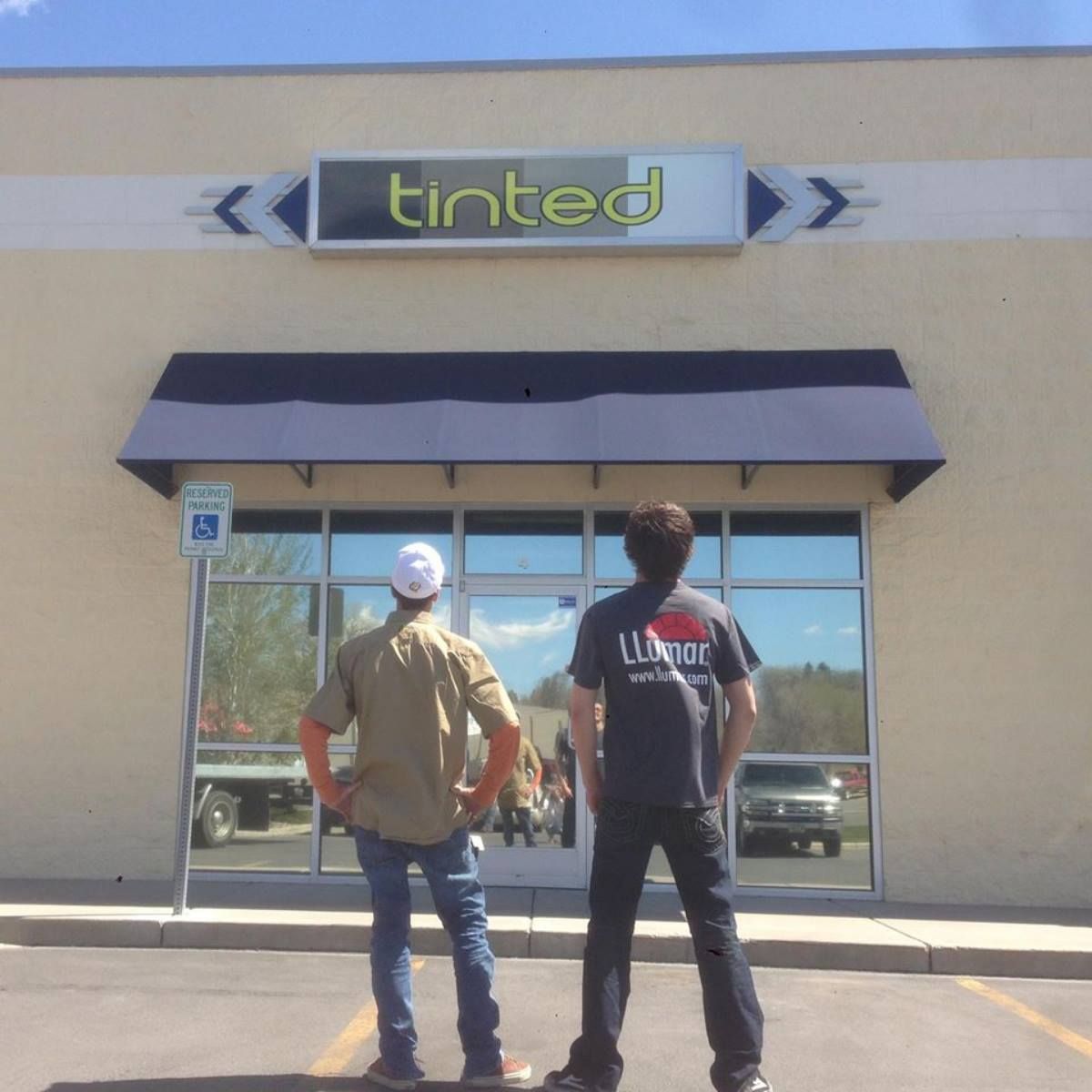Two men standing in front of a tinted store
