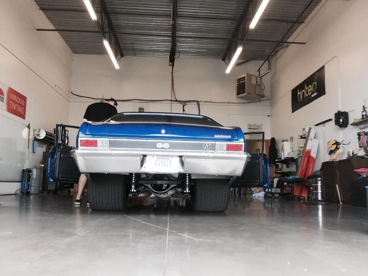 A blue chevy nova is parked in a garage