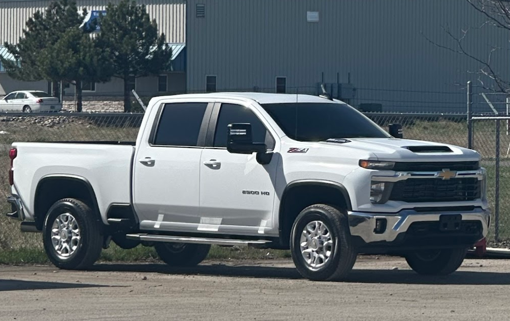 A white truck is parked on the side of the road in front of a building.