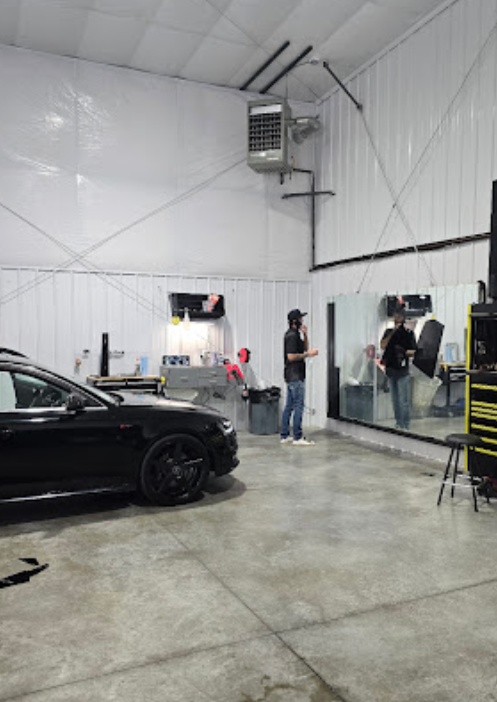 A black car is parked in a garage next to a mirror.