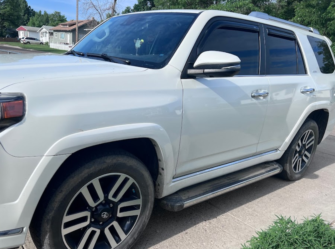 A white toyota 4runner is parked on the side of the road.