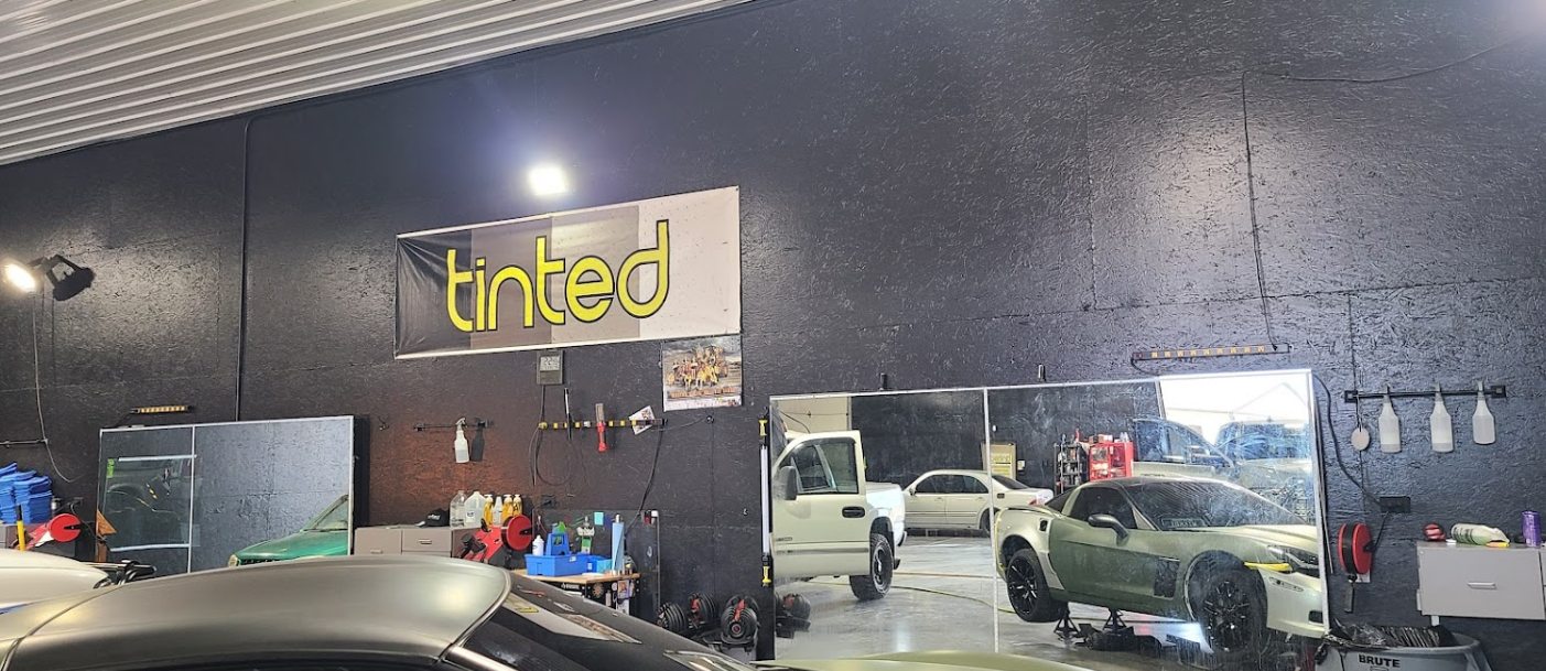 A car is parked in a garage with a sign that says tinted.
