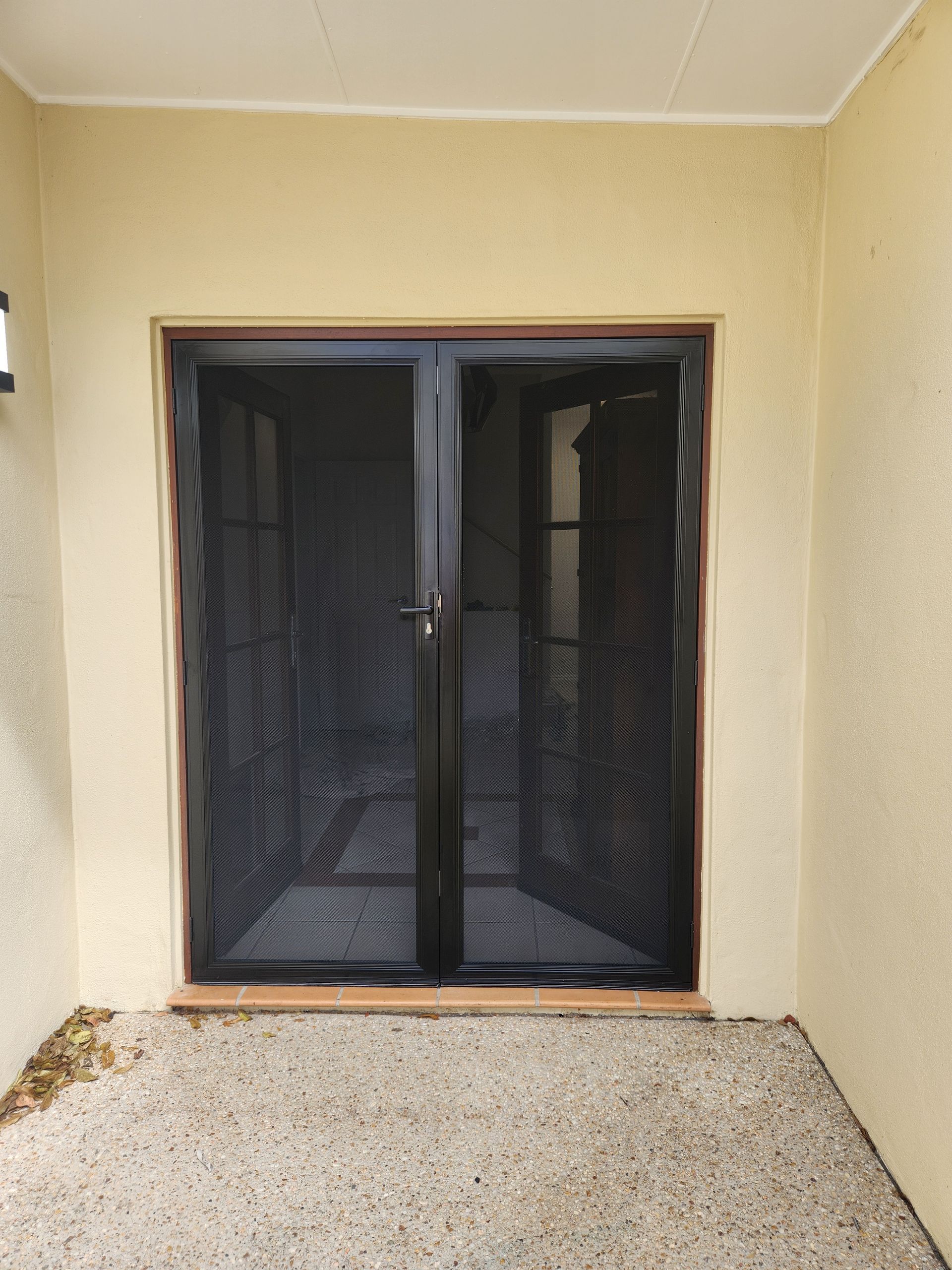 Black Security Screen Doors, Double Doors, Set in A Beige Wall, Gravel Floor — Smart Screens Qld in Ormeau, QLD