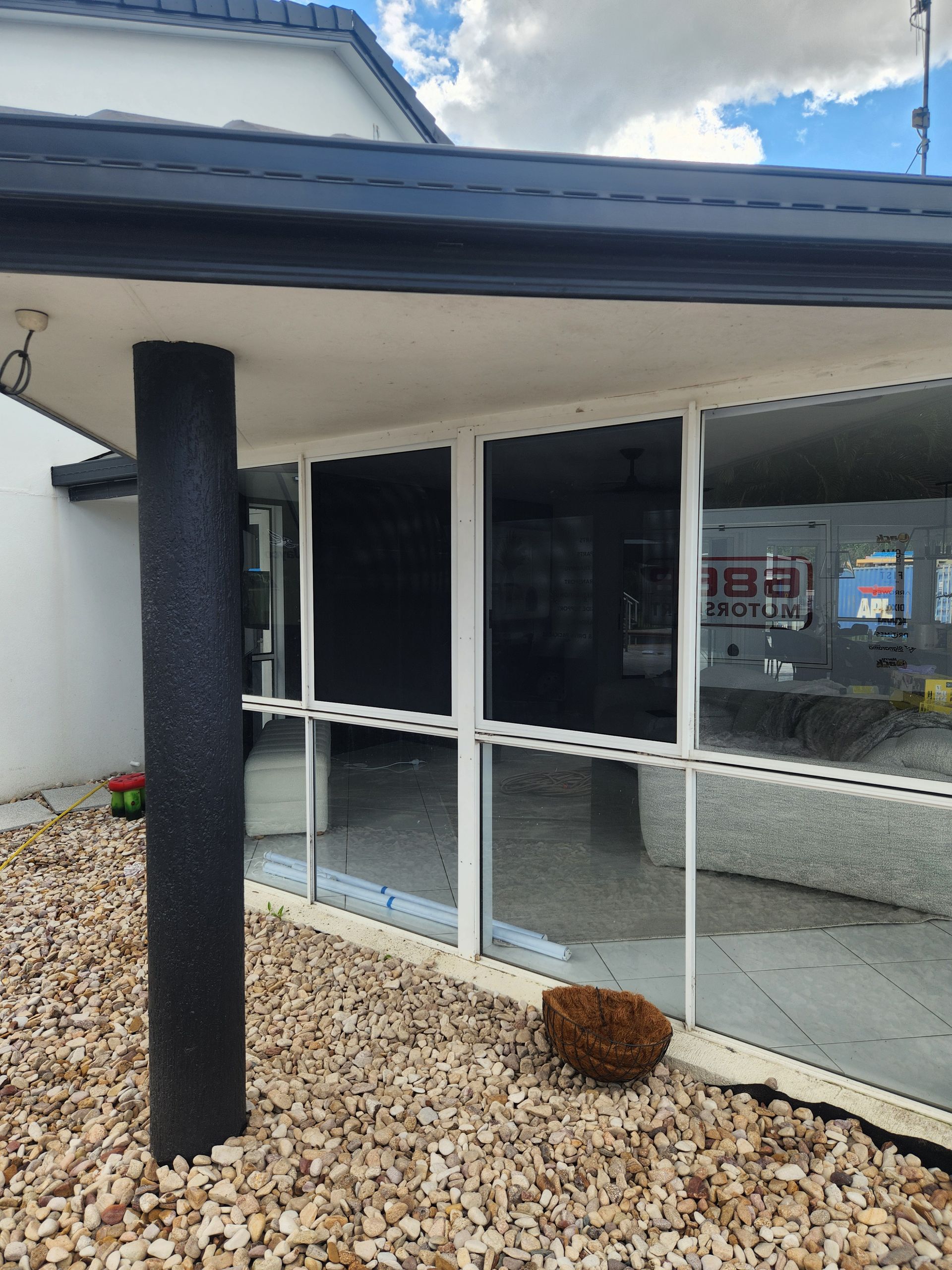 White House with Gray Roof, Bay Windows, and Gravel Landscaping — Smart Screens Qld in Ormeau, QLD