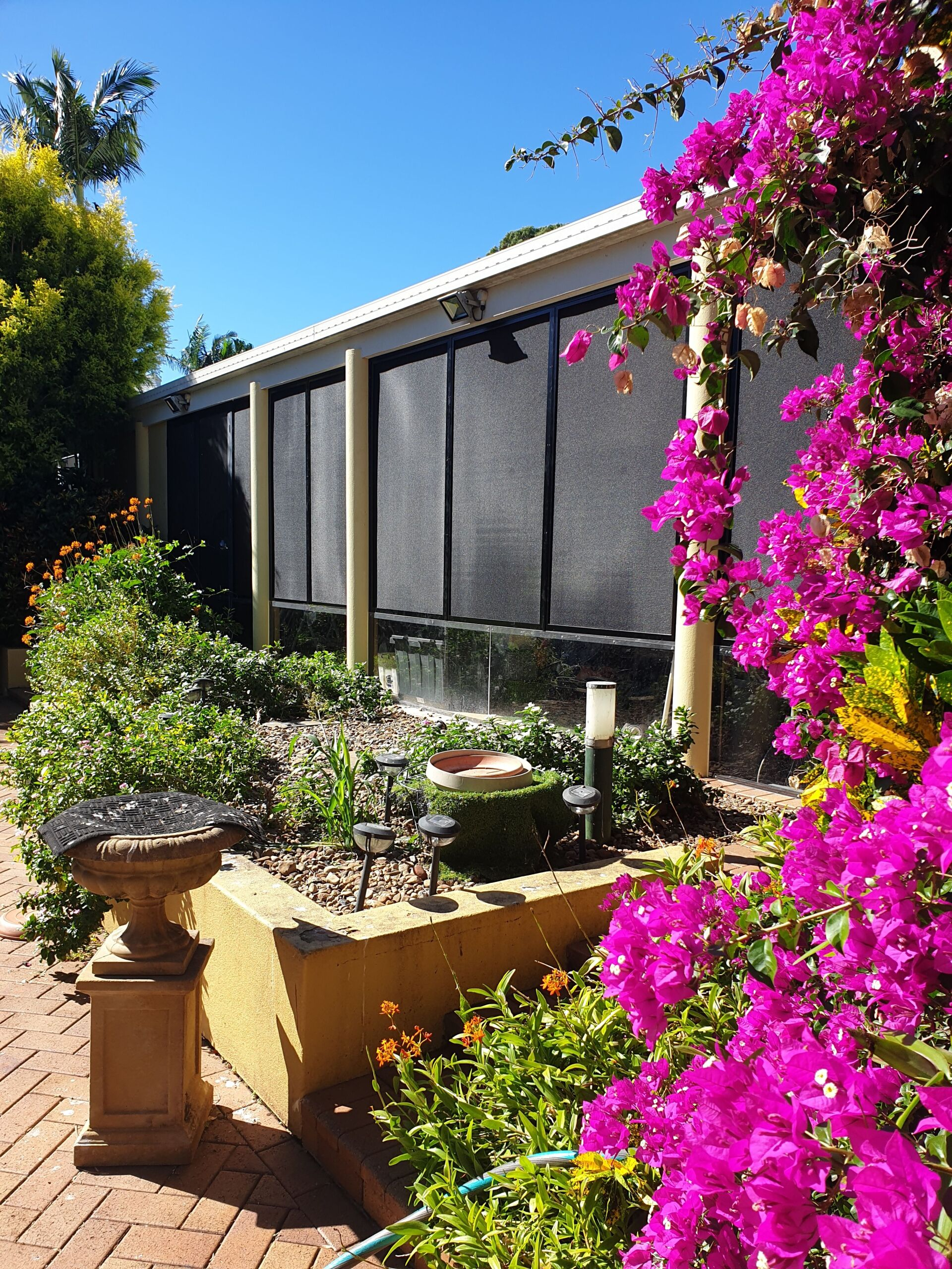 White Sliding Screen Door on A Patio with Tiled Floor and A Striped Reflection in The Glass Panel — Smart Screens Qld in Ormeau, QLD