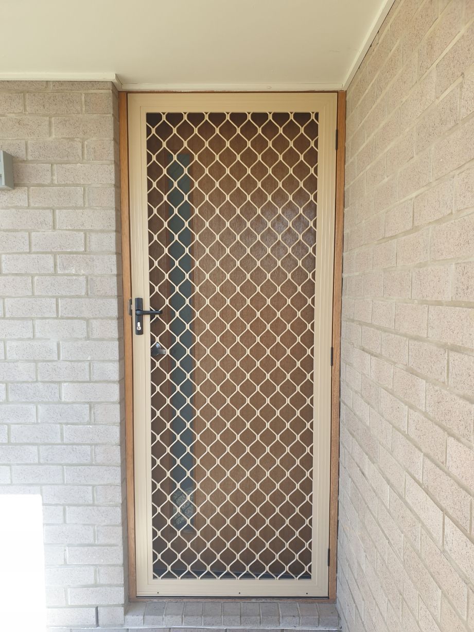 Beige Security Door with Diamond Mesh Screen in A Brick Doorway — Smart Screens Qld in Ormeau, QLD