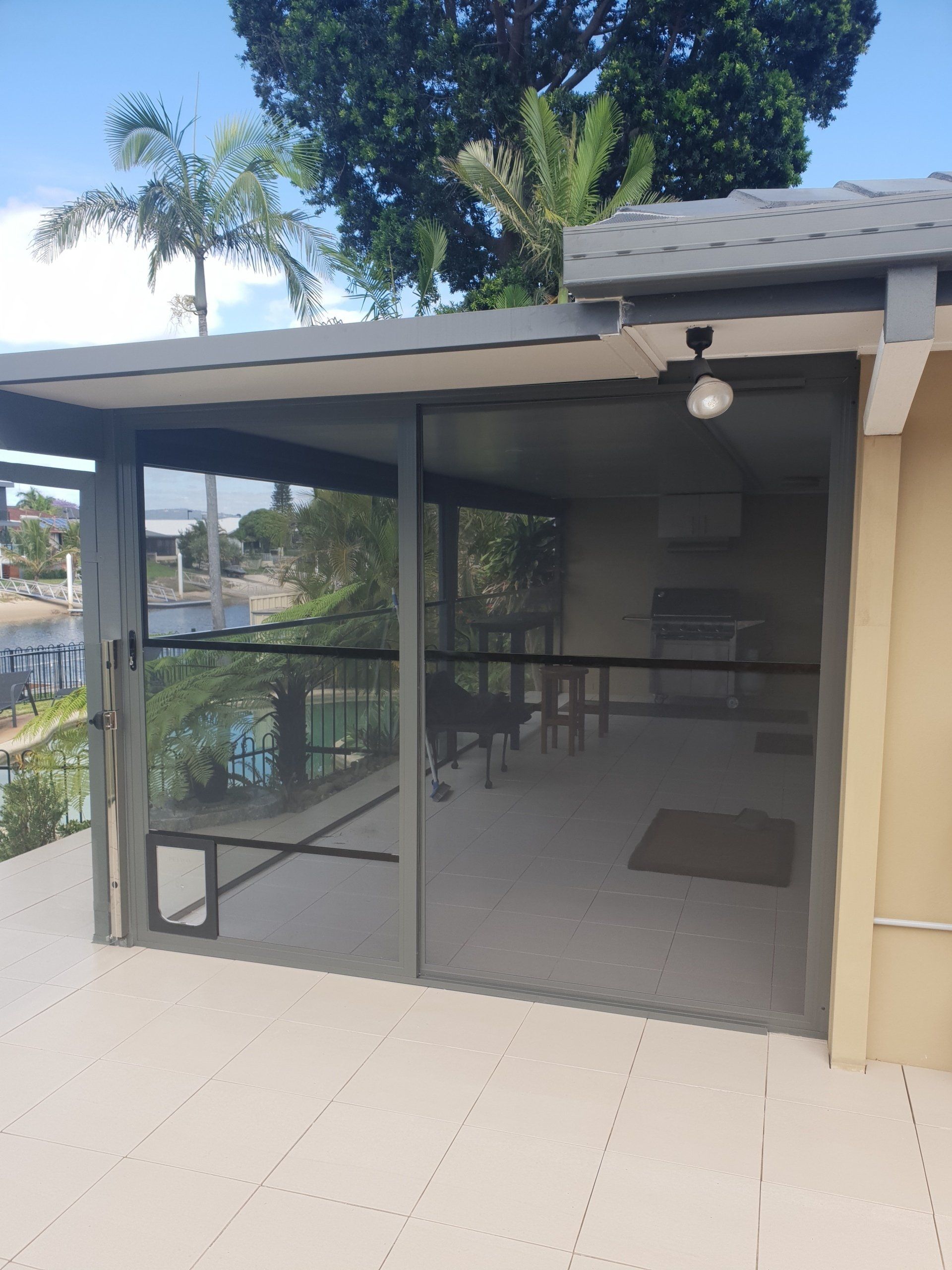 Screened Patio with Outdoor Table, Chairs, and A Ceiling Fan Beside a Pool and Trees — Smart Screens Qld in Ormeau, QLD