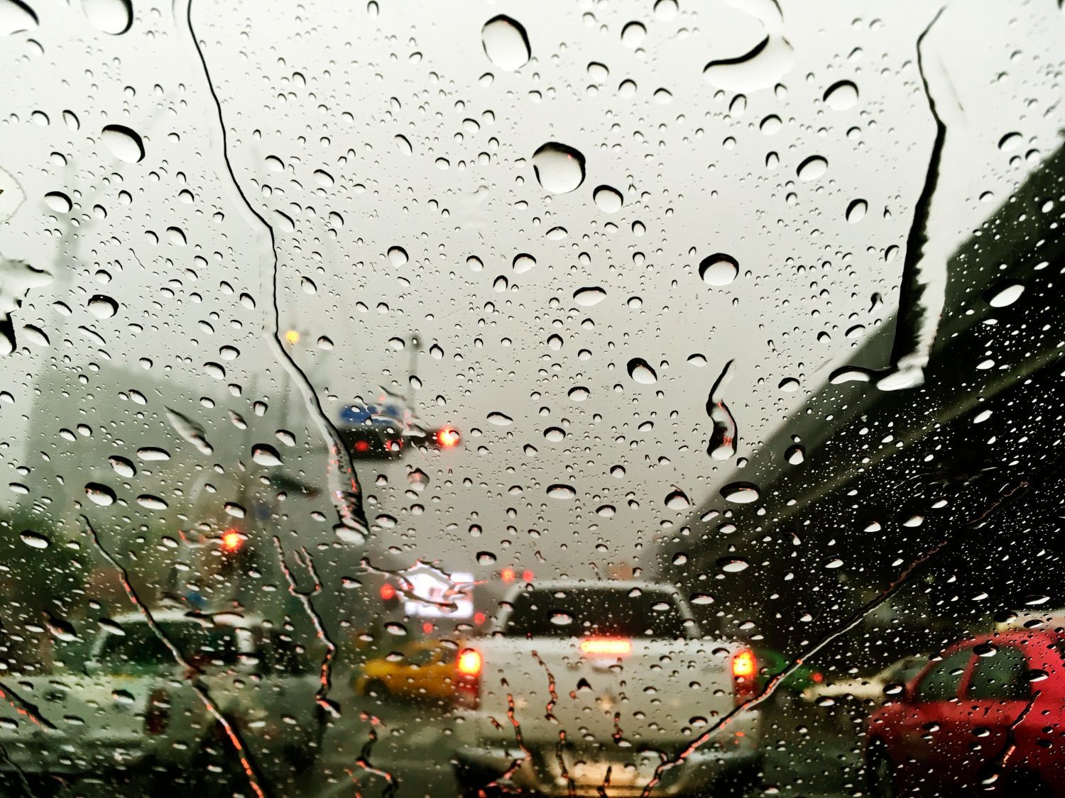 Rain-covered windshield with traffic; a white pickup truck and other vehicles visible.
