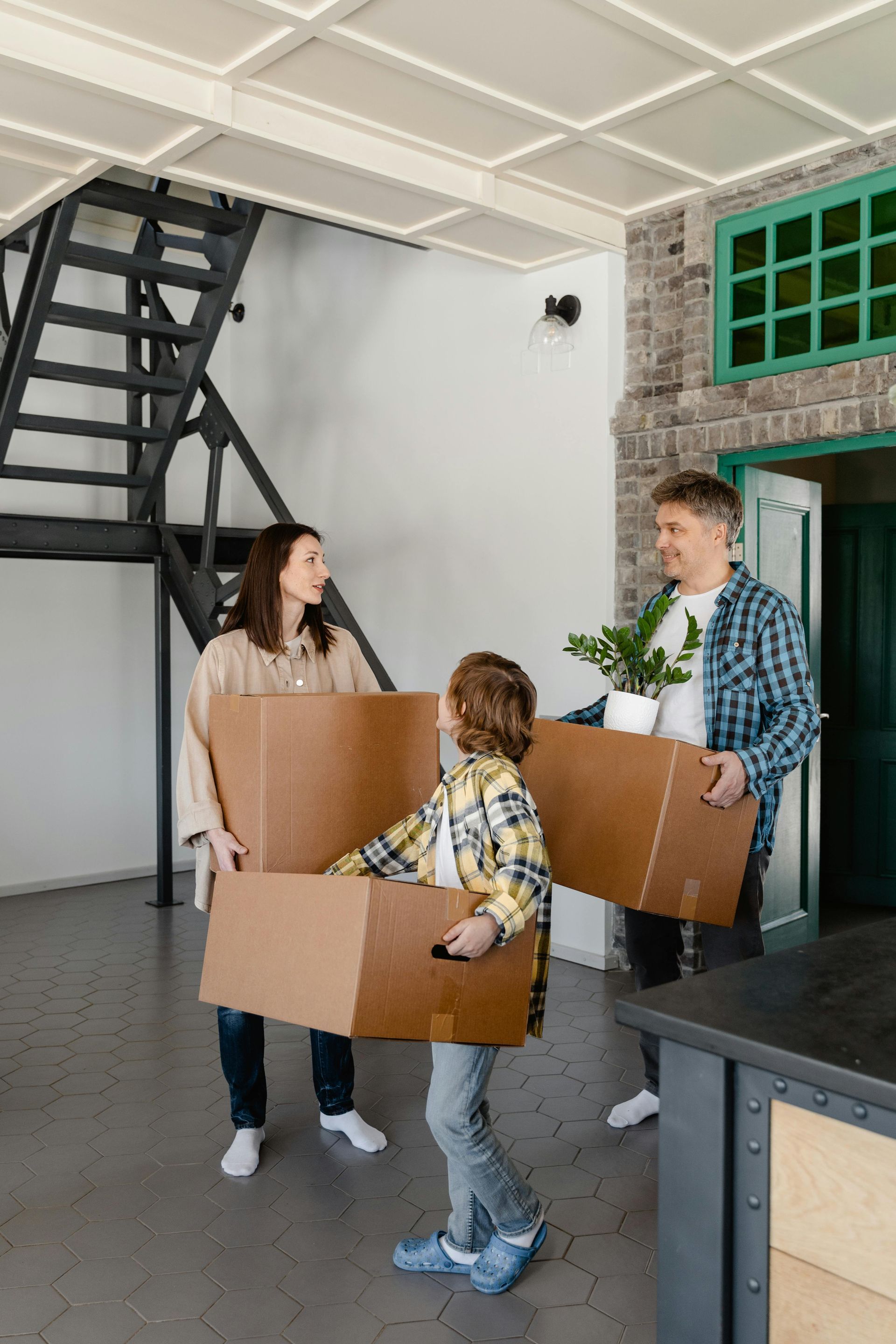 Family carrying boxes moving into a new home.