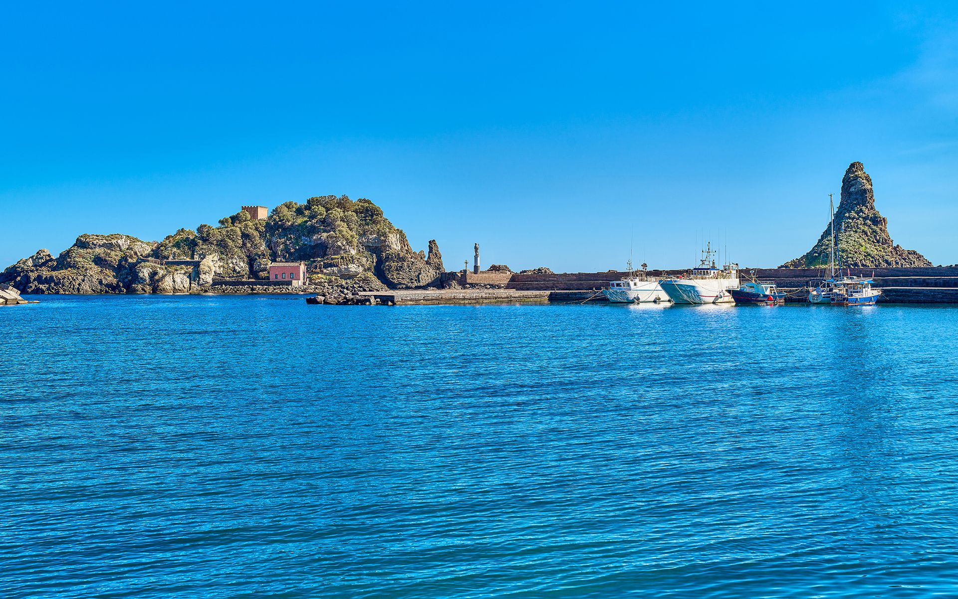 Un grande specchio d'acqua con barche al suo interno e una piccola isola sullo sfondo.