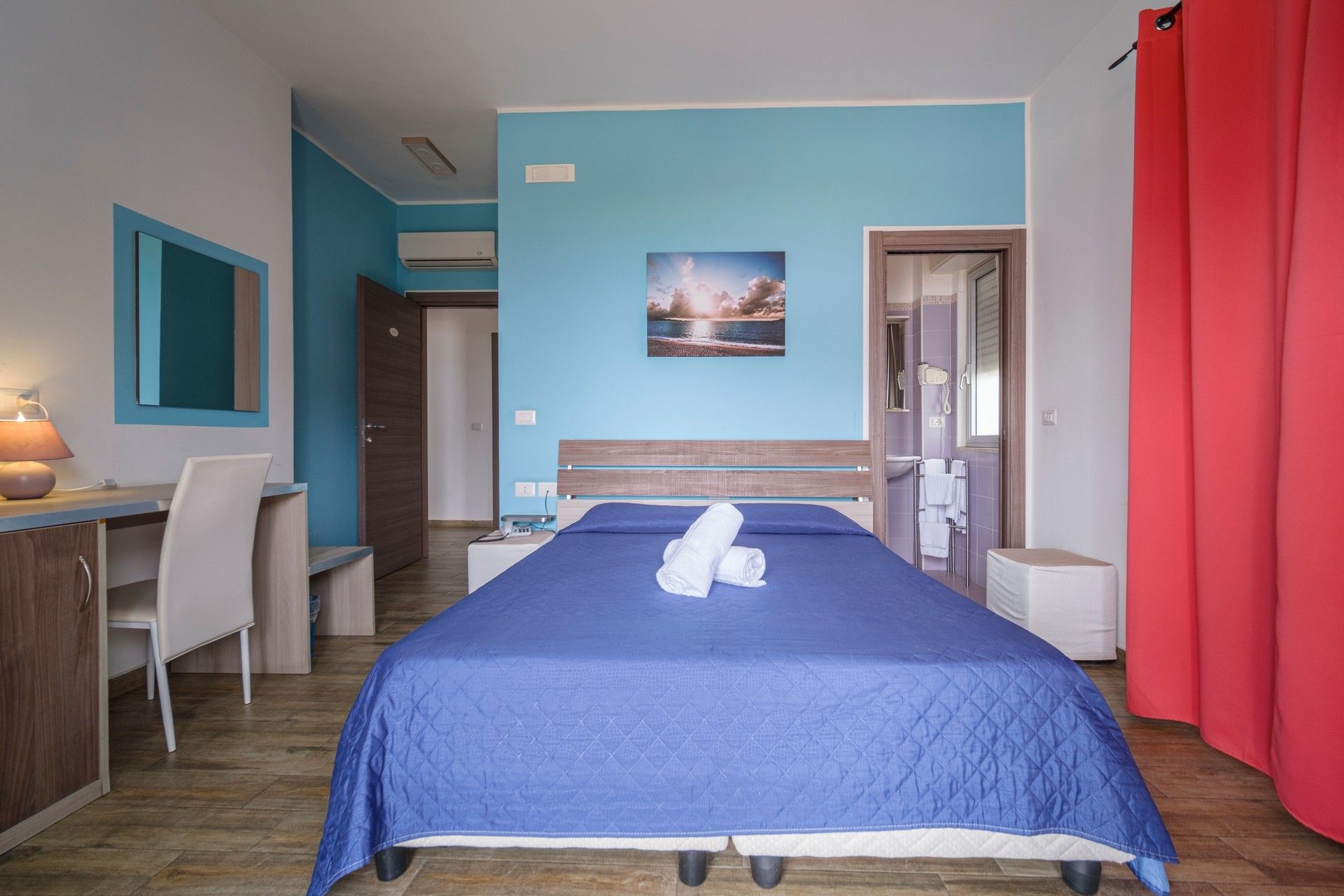 Una camera d'albergo con letto, scrivania, sedie e televisione.