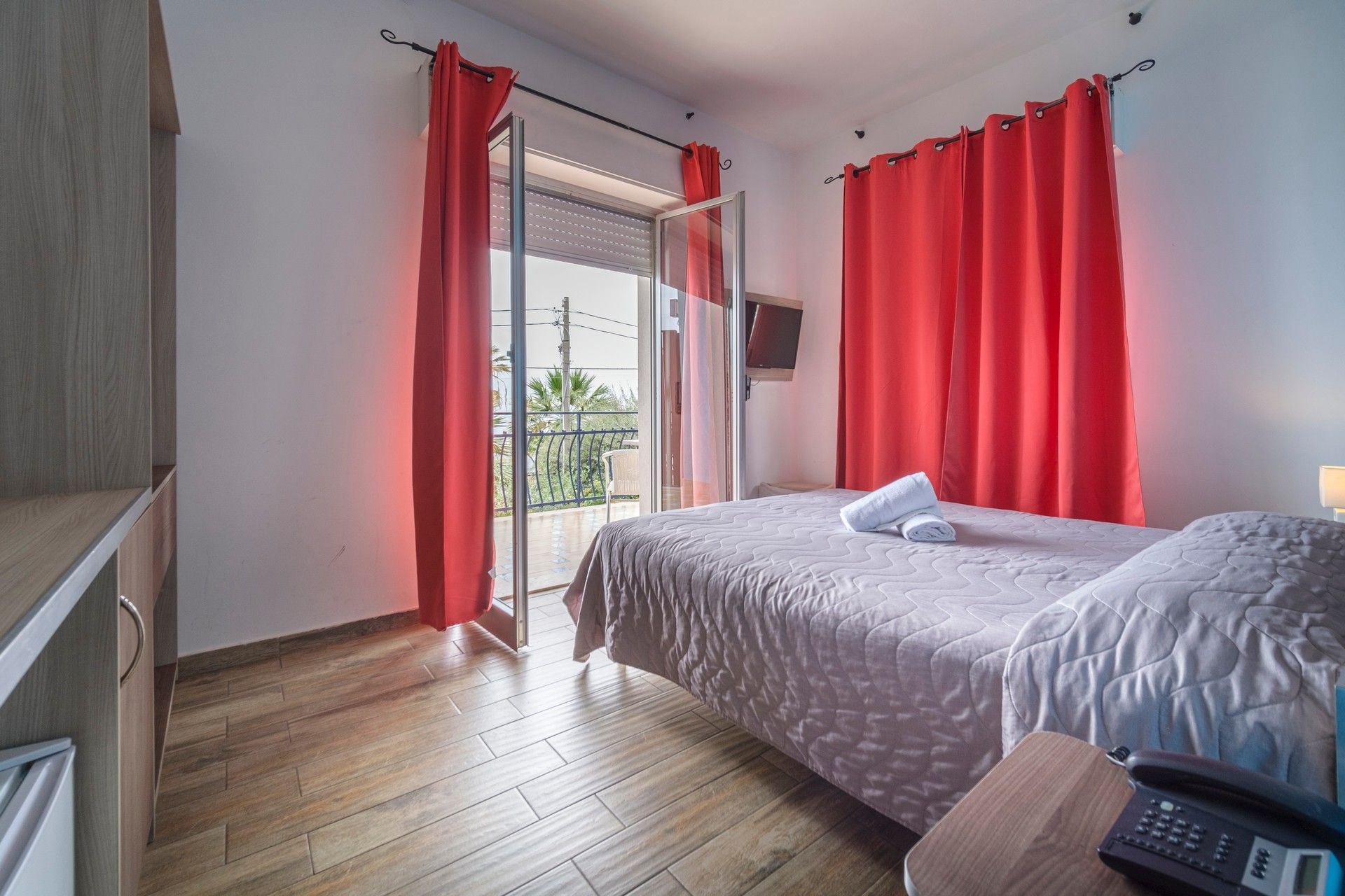 Una camera d'albergo con un letto king size e tende rosse.