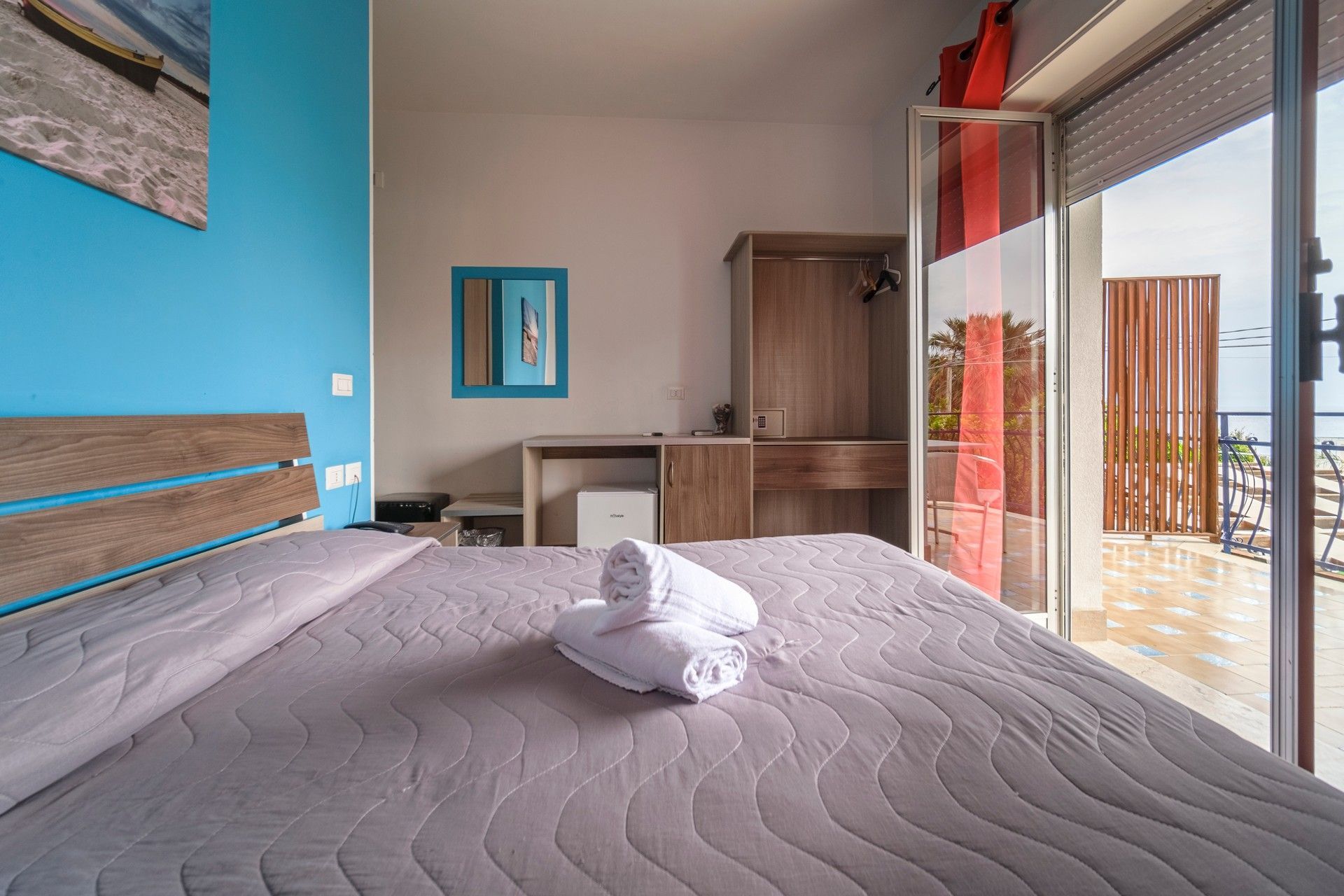 Una camera con un letto, asciugamani e una porta scorrevole in vetro.