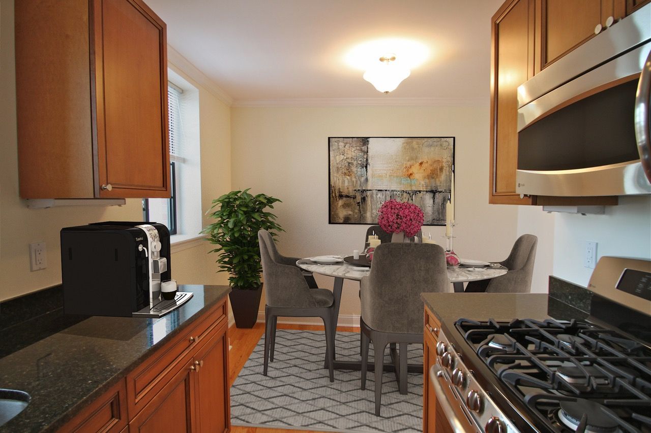 Open kitchen with granite counters, stainless stove, microwave, and a dining table with chairs.