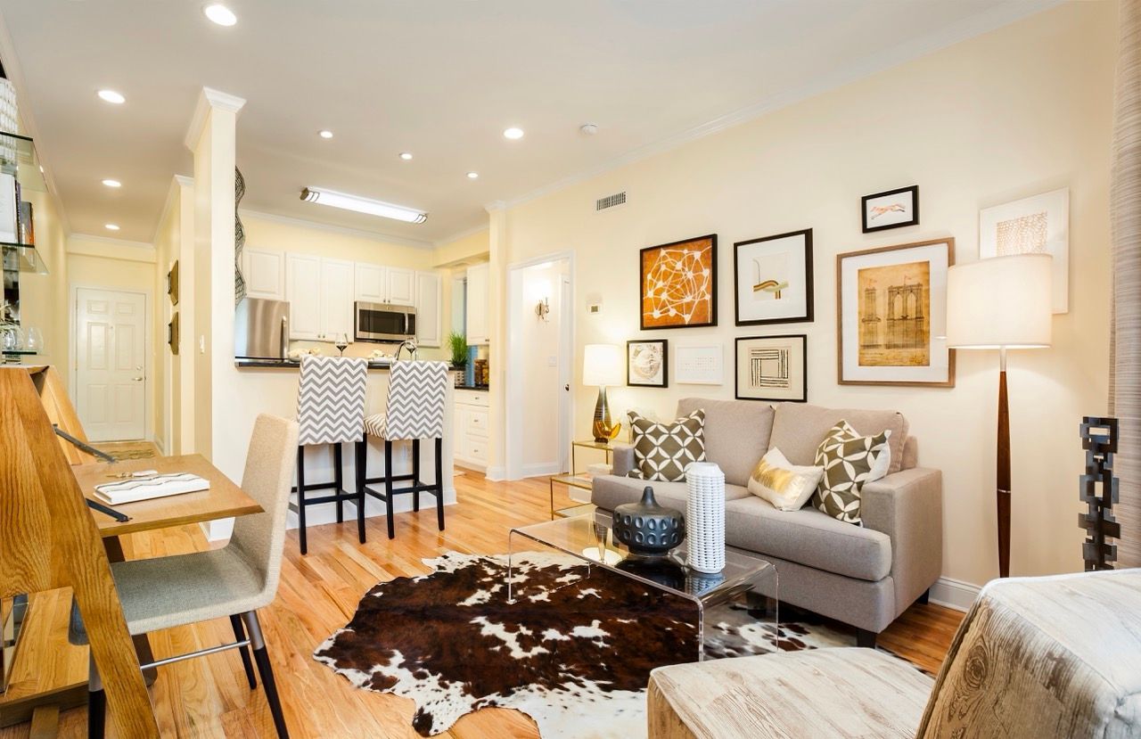 Open-concept living area with beige sofa, glass coffee table, and kitchen bar seating.