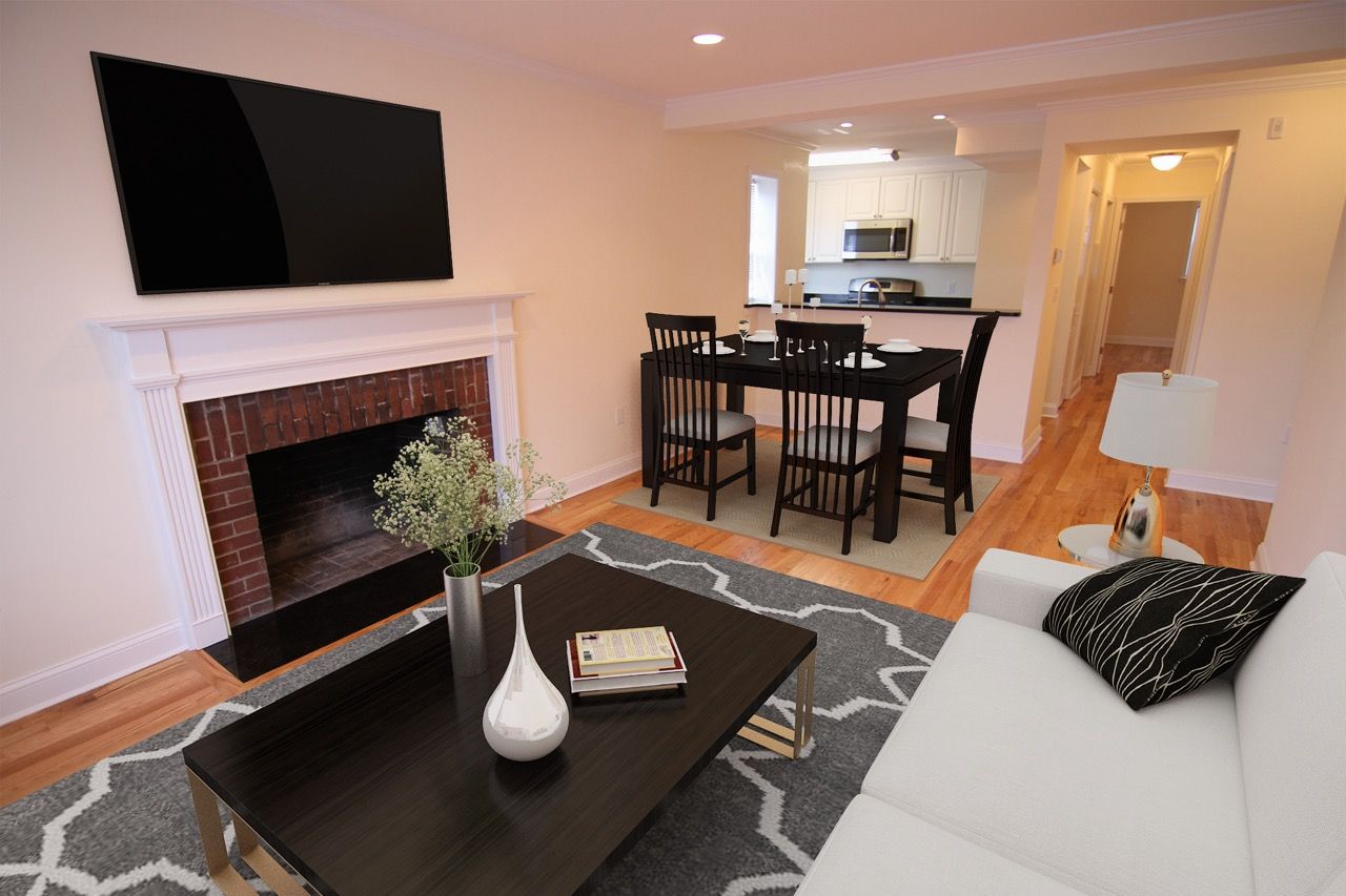 Living room in an apartment with a sofa, coffee table, fireplace, and mounted TV.