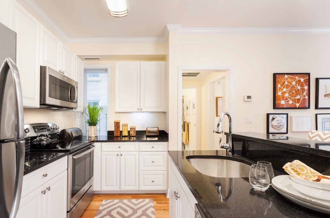 Bright kitchen with white cabinets, black granite countertops, and stainless-steel appliances.