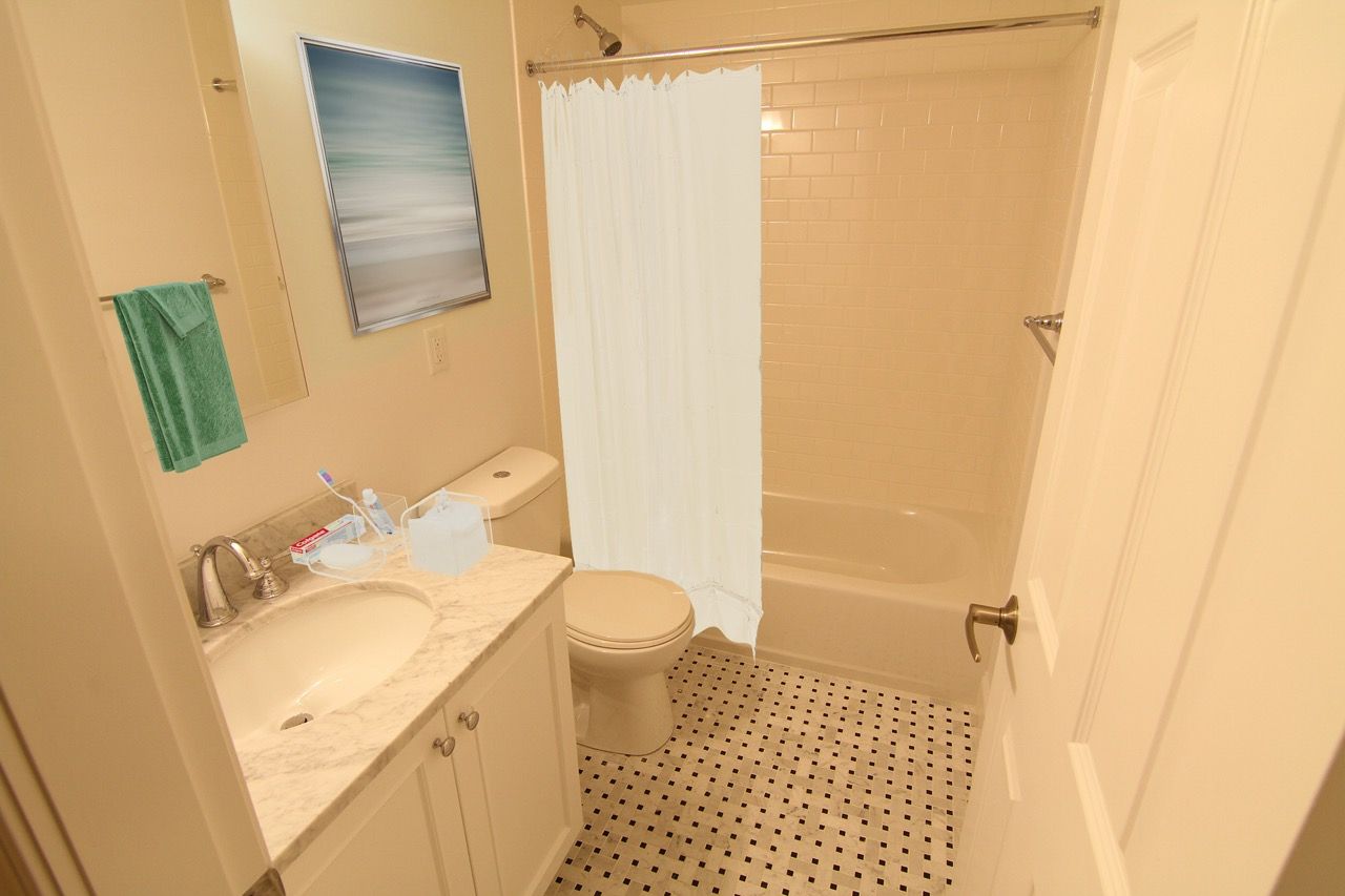 Compact apartment bathroom with vanity, toilet, and a tub/shower with curtain.