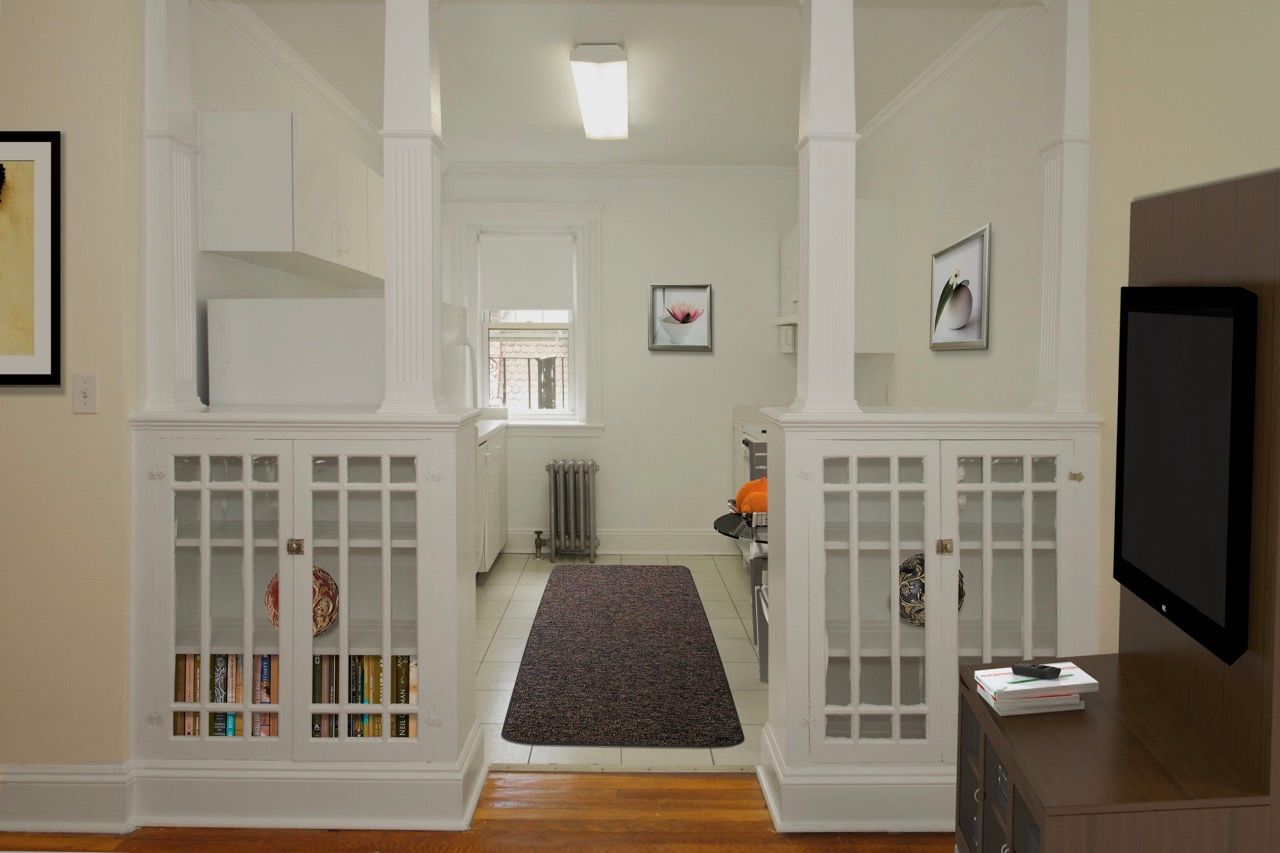 Entryway of an apartment with white built-in cabinets and a view into the kitchen.
