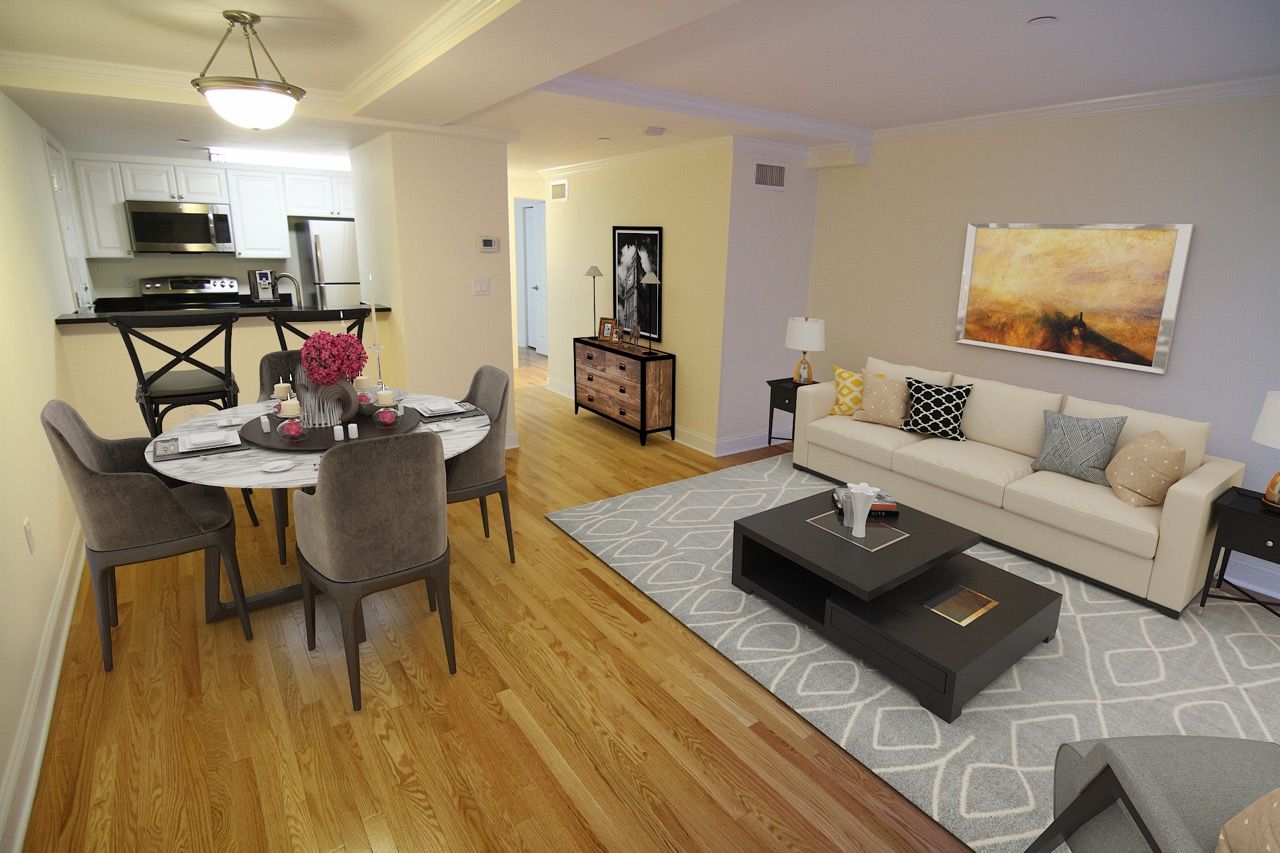 Open-concept living room and dining area in a modern apartment with hardwood floors.