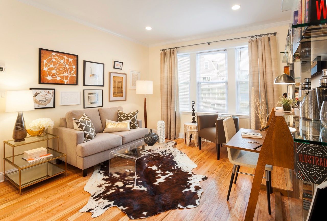 Cozy apartment living room with beige sofa, wall art, and a cowhide rug.