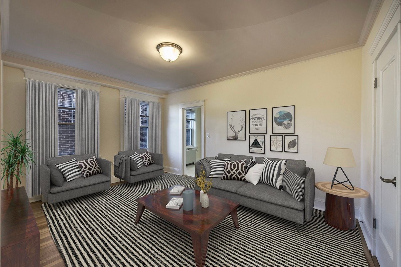 Living room in an apartment with two gray sofas, a striped rug, and wall art.