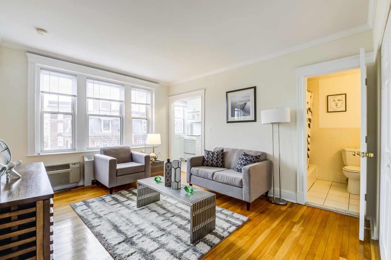 Bright living room in an apartment with two gray sofas, a coffee table, and hardwood floors.