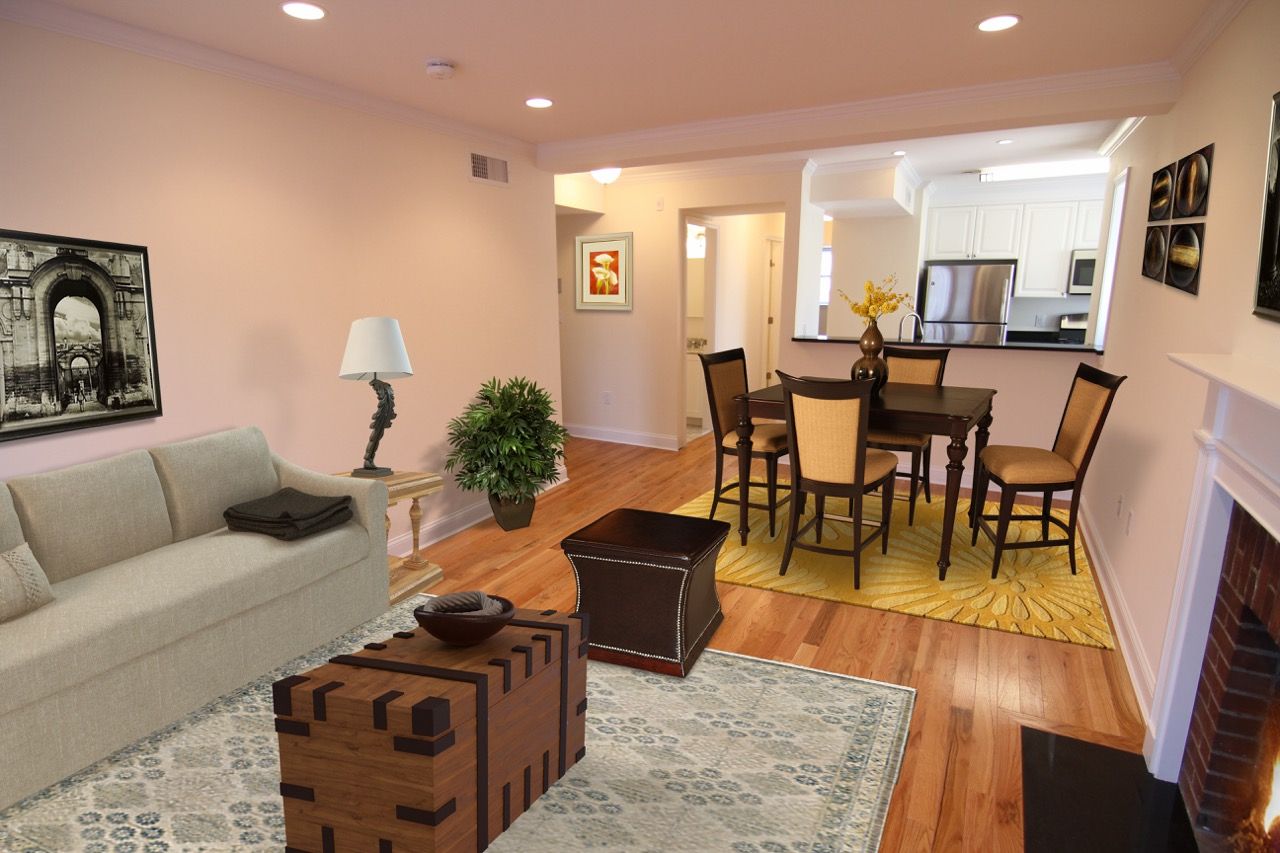 Open living room and dining area in a furnished apartment, with hardwood floors and a visible kitchen.