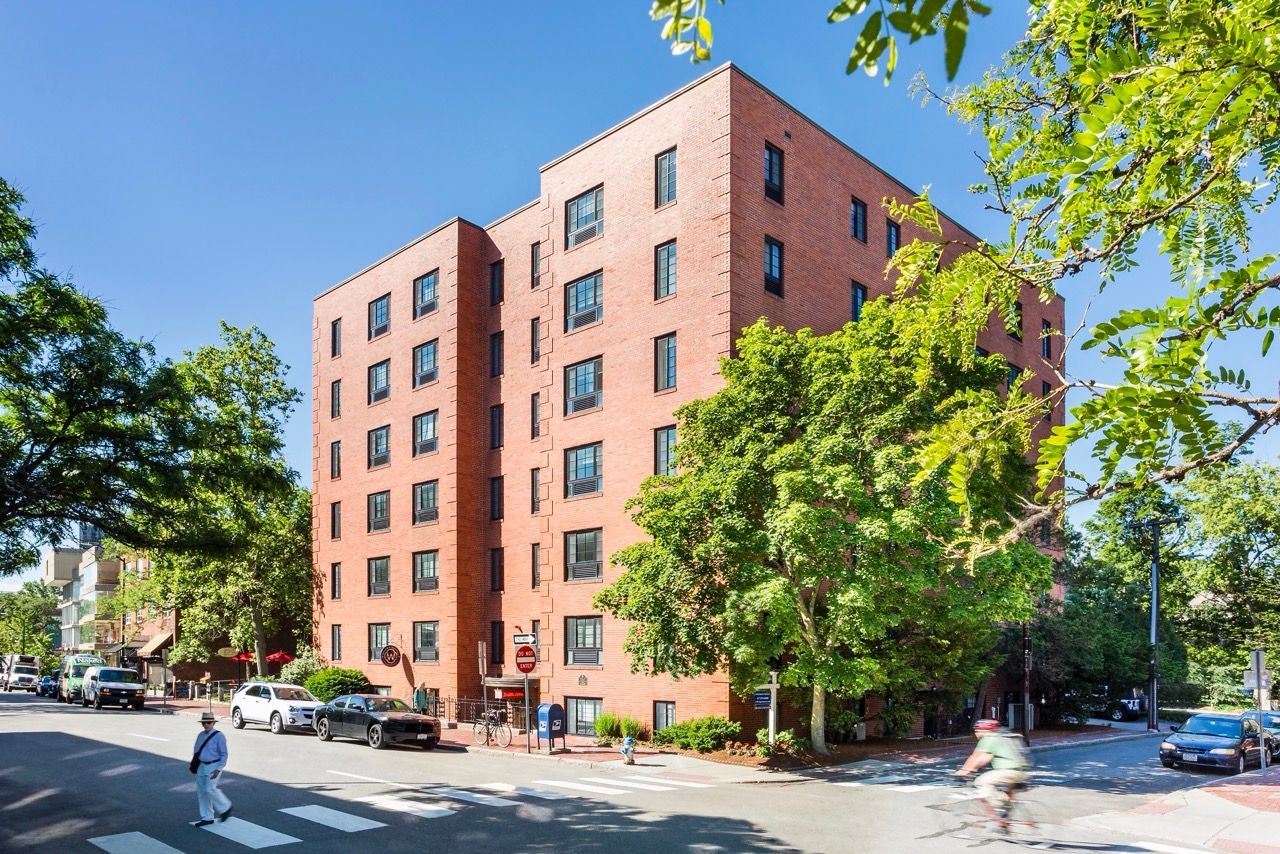 Brick mid-rise apartment building on a tree-lined street corner.