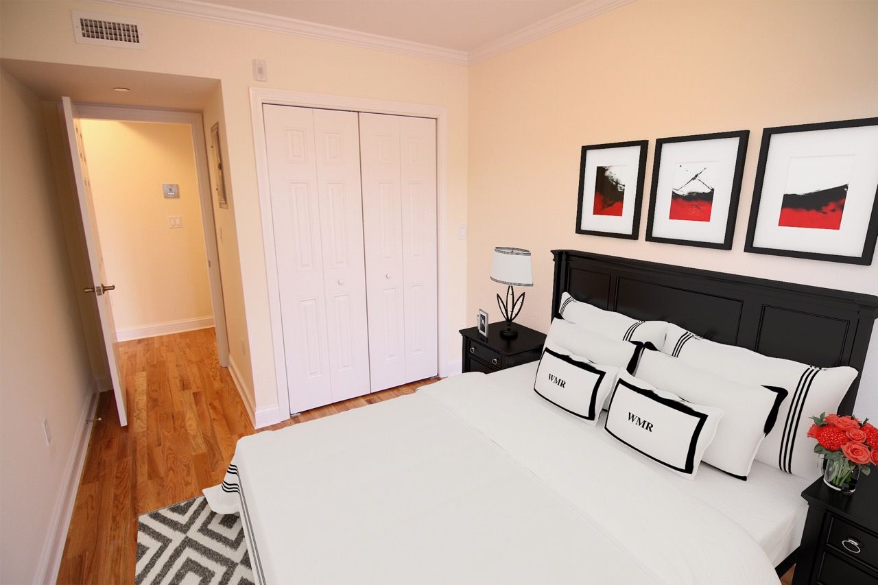 Bedroom with a black bed frame, white bedding, two nightstands, and framed art.