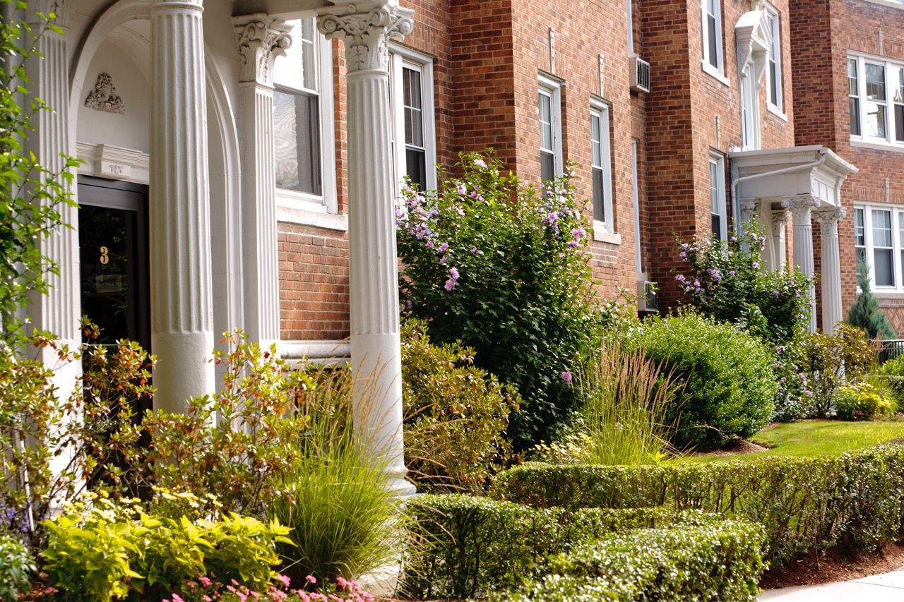 Brick apartment building with columned entry and well-kept landscaping.