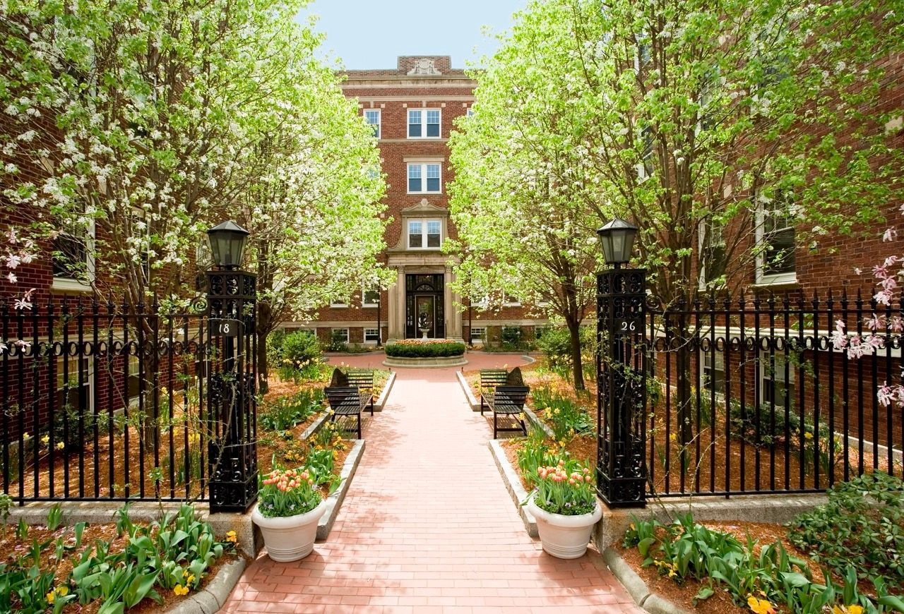 Brick apartment courtyard with iron gates, brick walkway, and flowering trees.