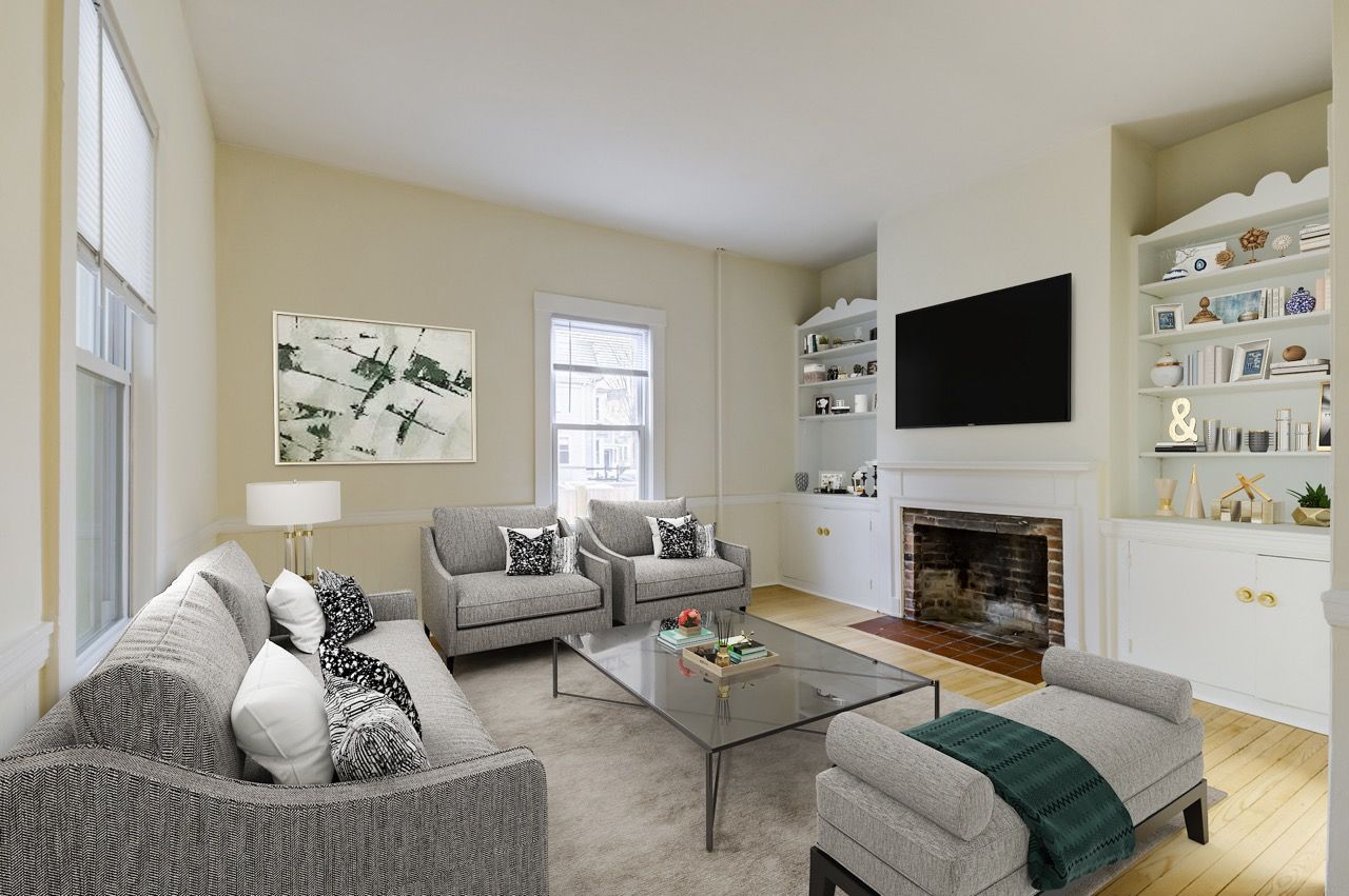 Living room in an apartment with grey sofas, glass coffee table, built-in shelves, and a fireplace.