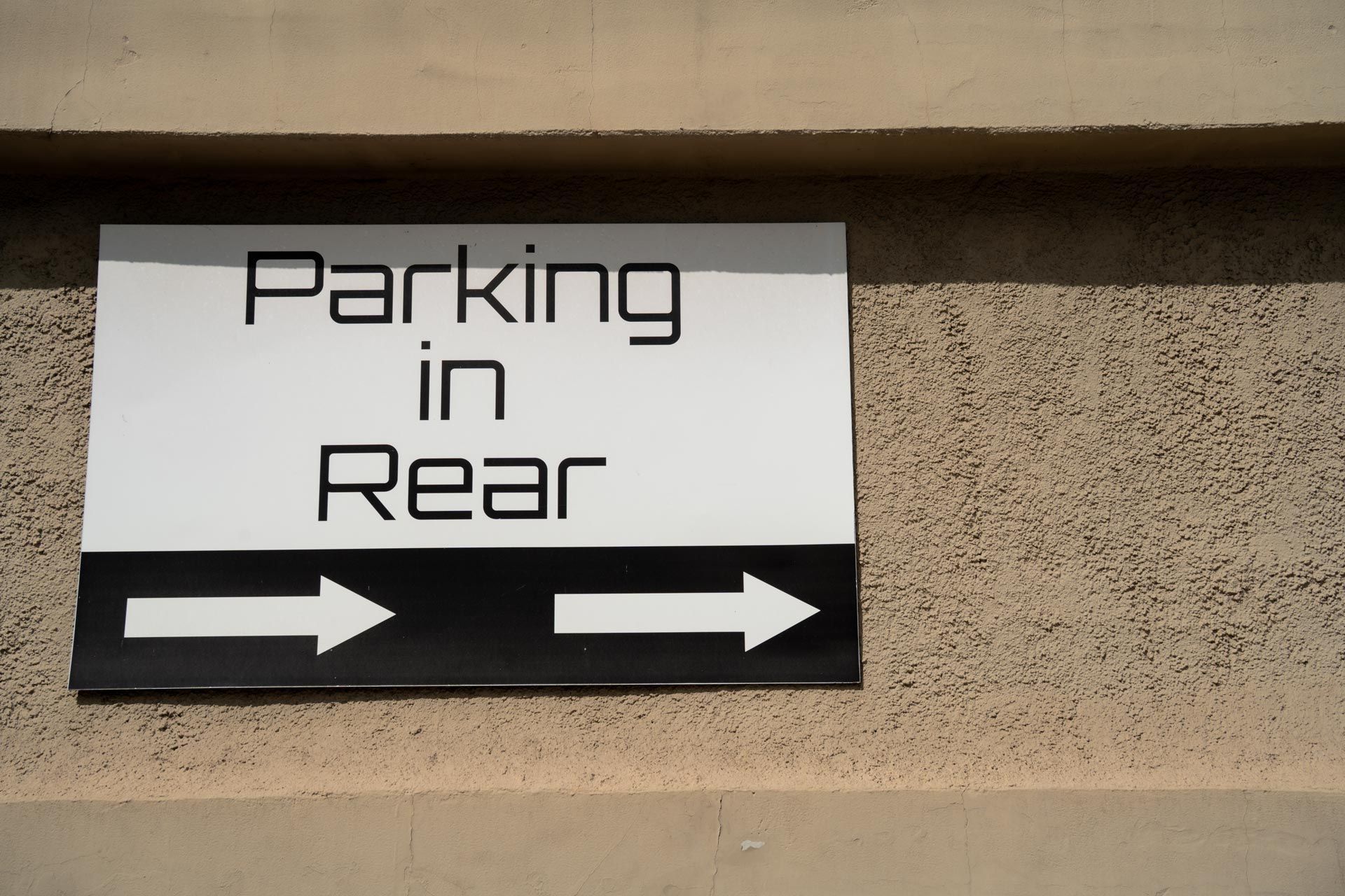 Parking in rear sign with directional arrows on textured wall. Parking in rear sign with directional arrows on textured wall.