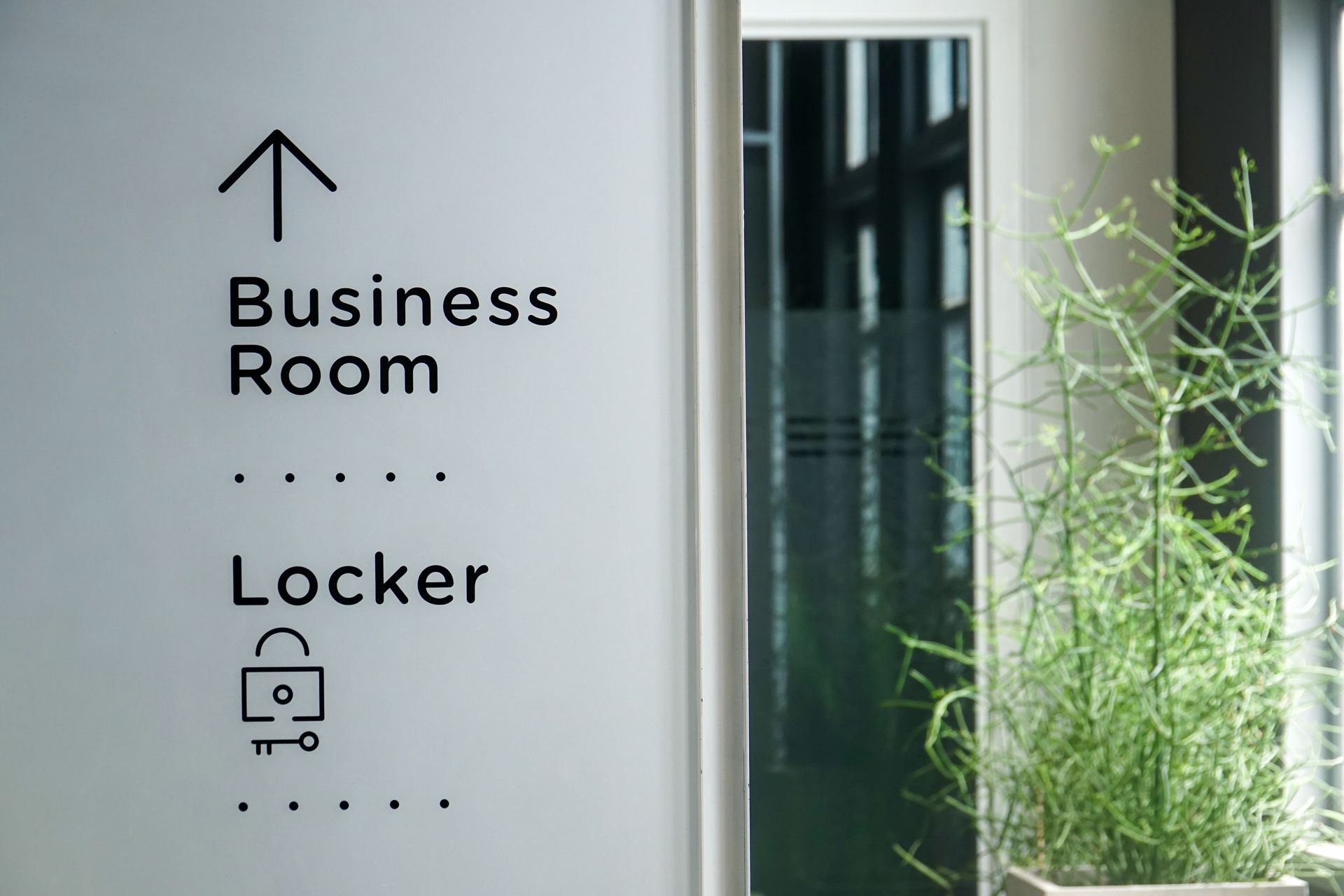 Wall sign showing directions to the business room and locker area in a modern office. Wall sign showing directions to the business room and locker area in a modern office.