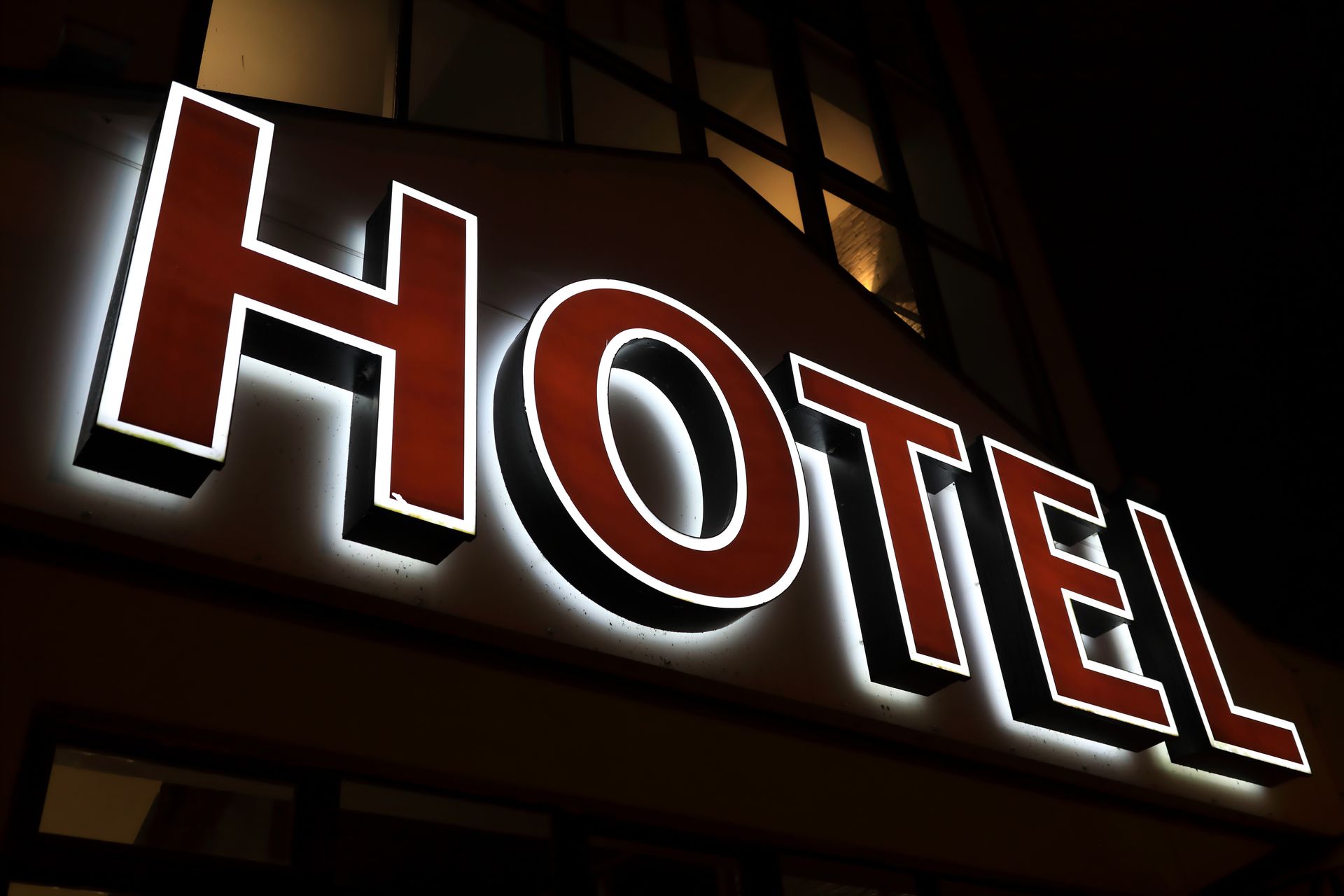 Illuminated “HOTEL” sign on building facade at night.