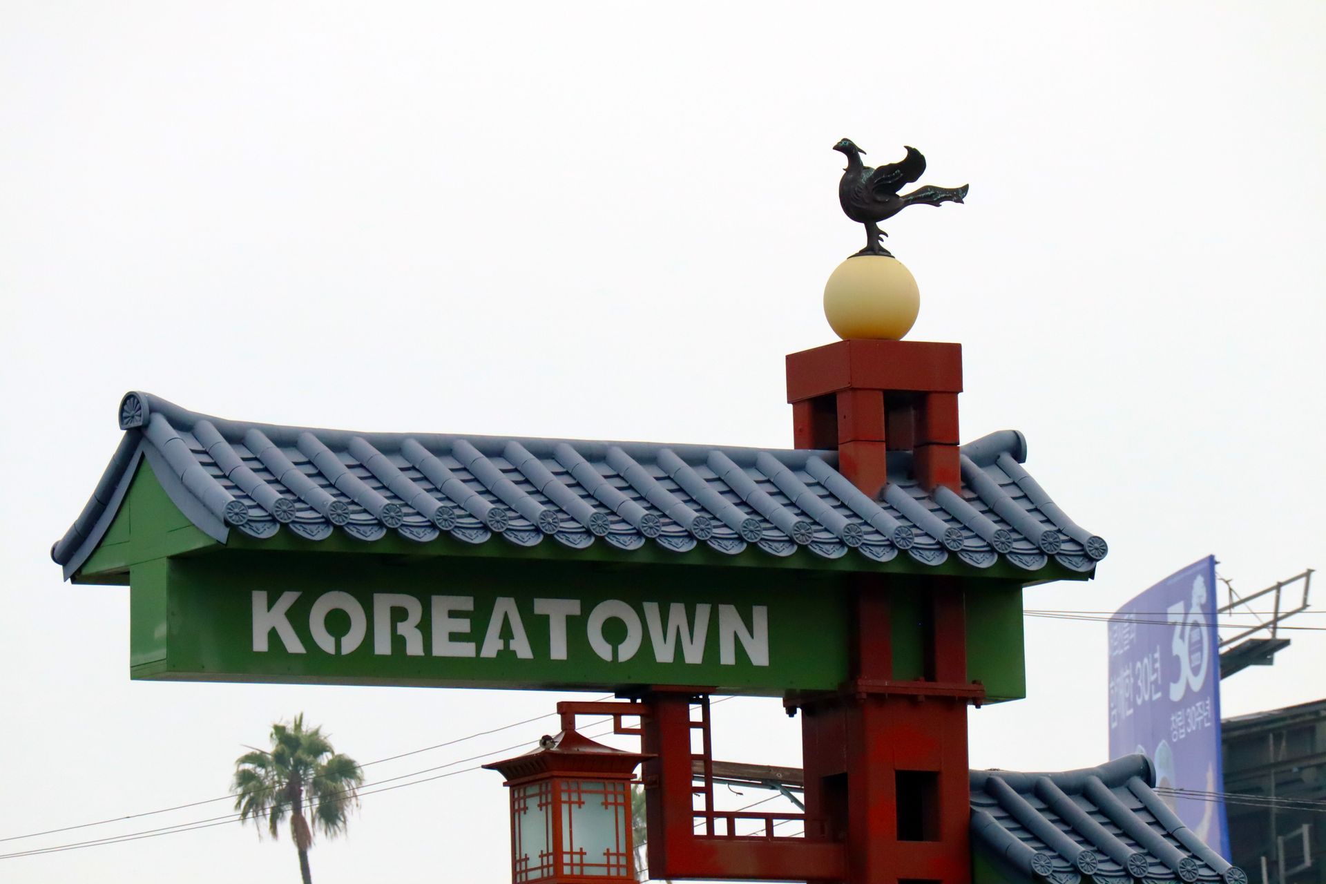 Koreatown entrance sign with blue roof and a rooster statue on top