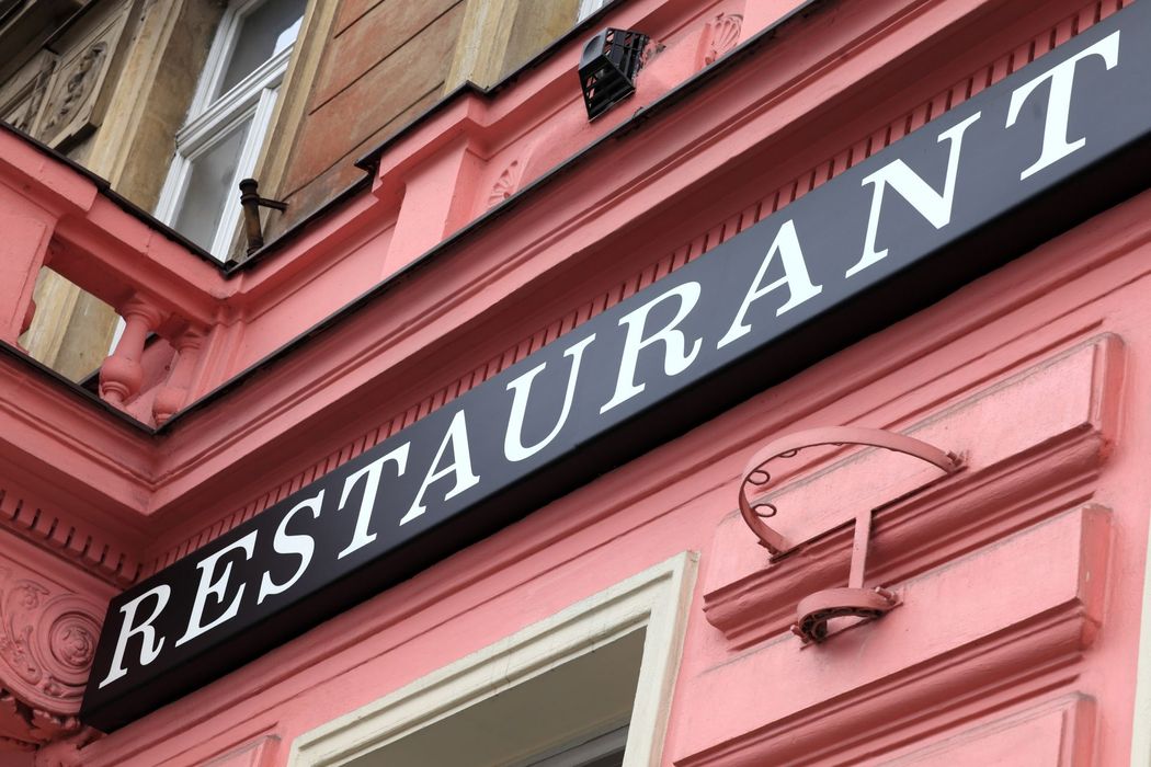 Bold RESTAURANT sign pops on pink storefront with vintage trim.